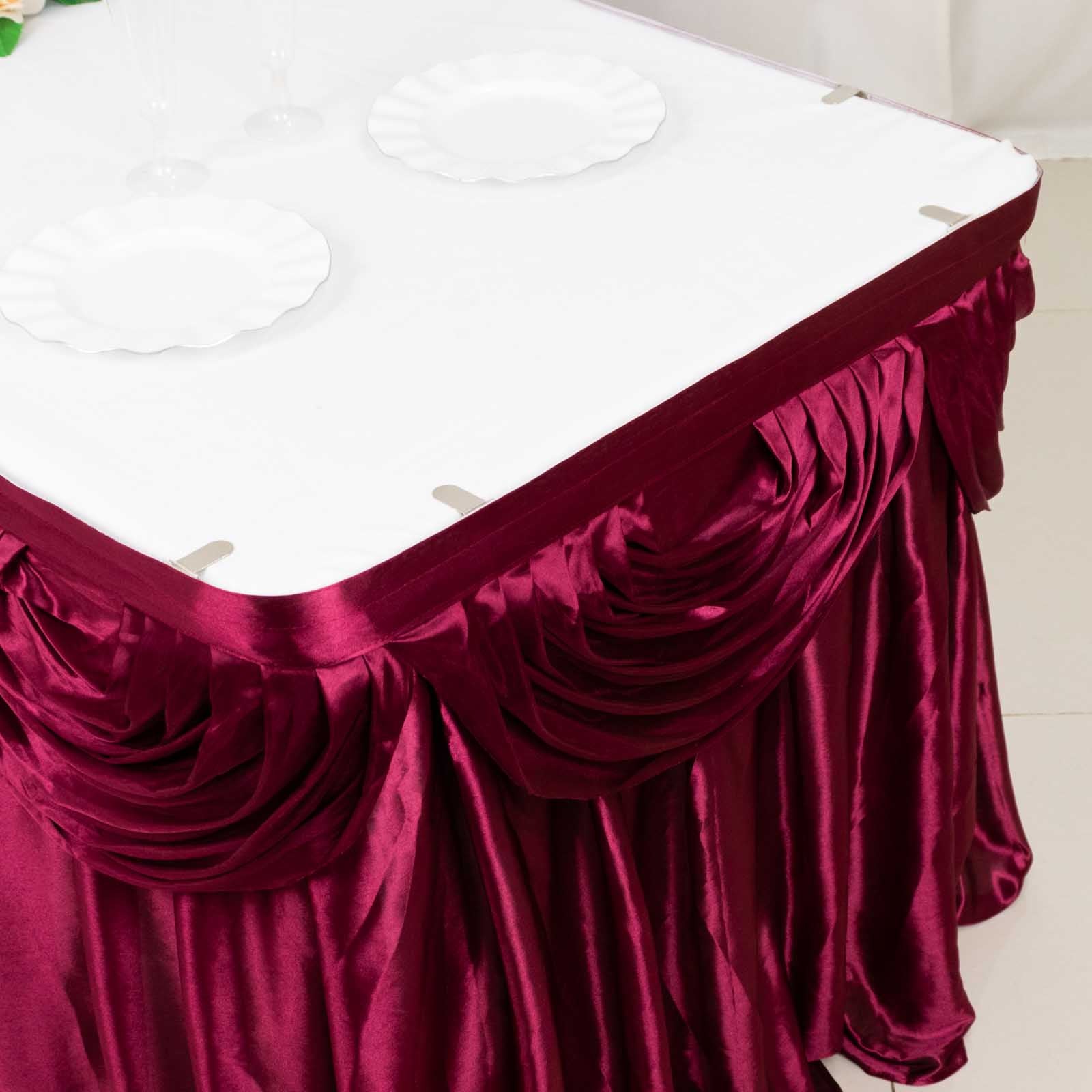 Burgundy pleated satin table skirt draped elegantly over a table.