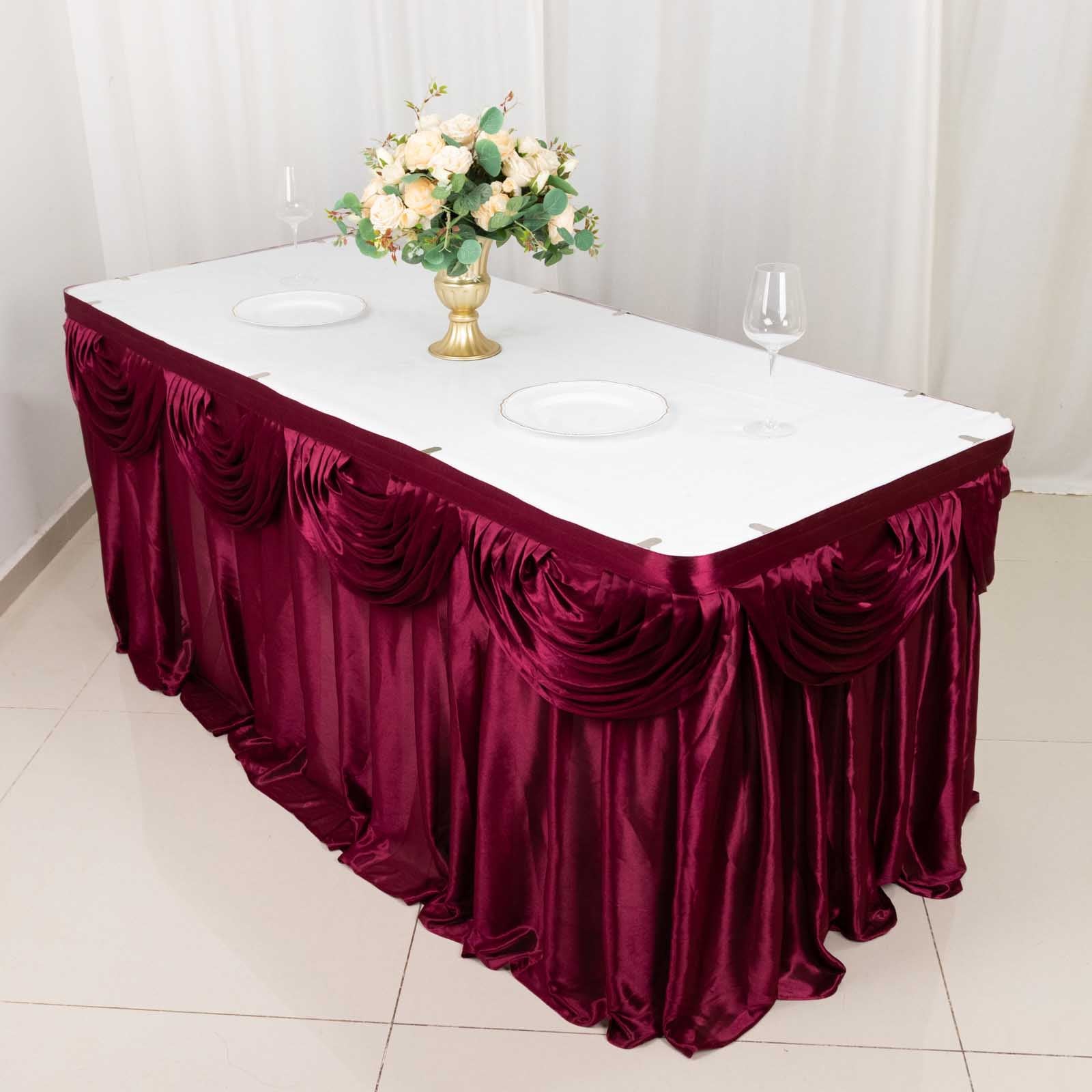 Burgundy pleated satin table skirt draped elegantly around a table.
