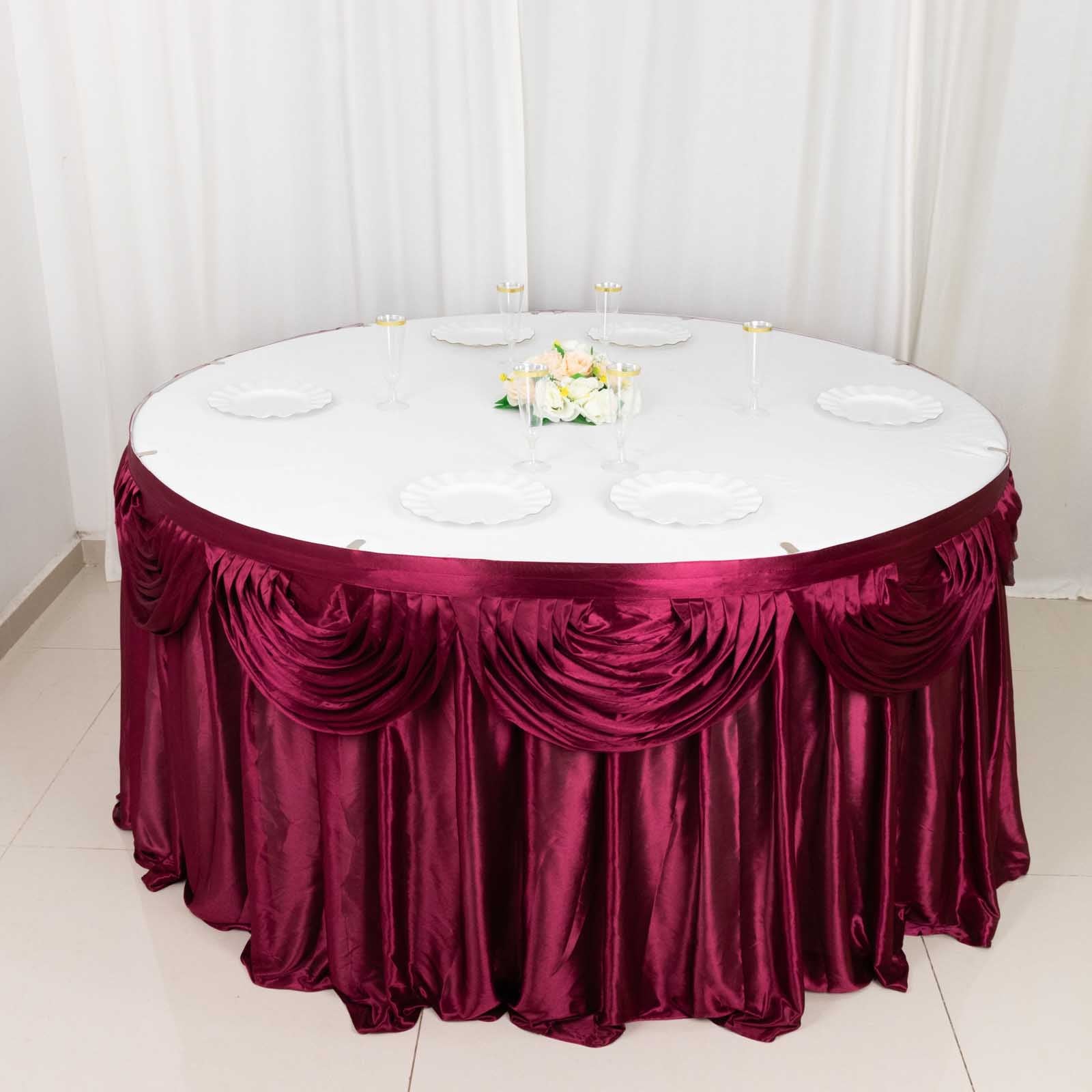 14ft burgundy pleated satin double drape table skirt on a round table.