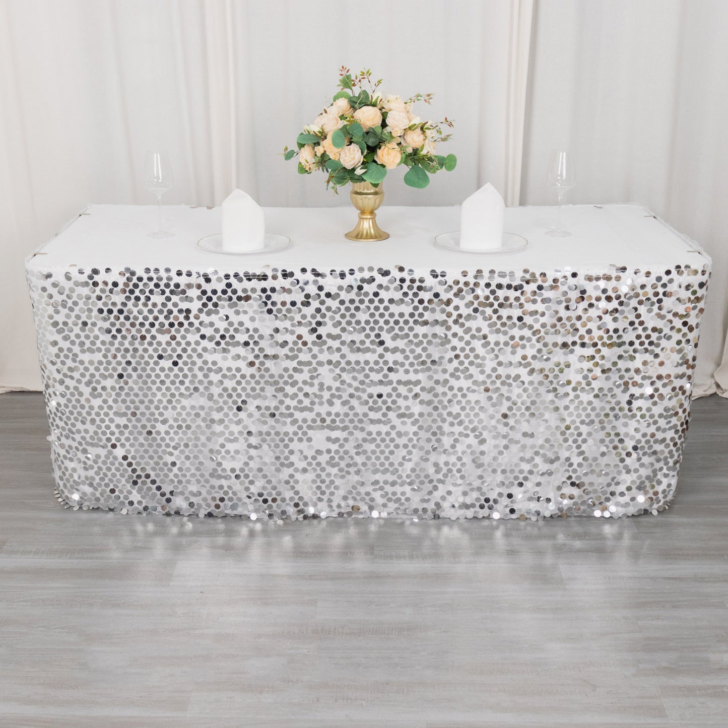 Silver sequin table skirt on a decorated table with flowers.