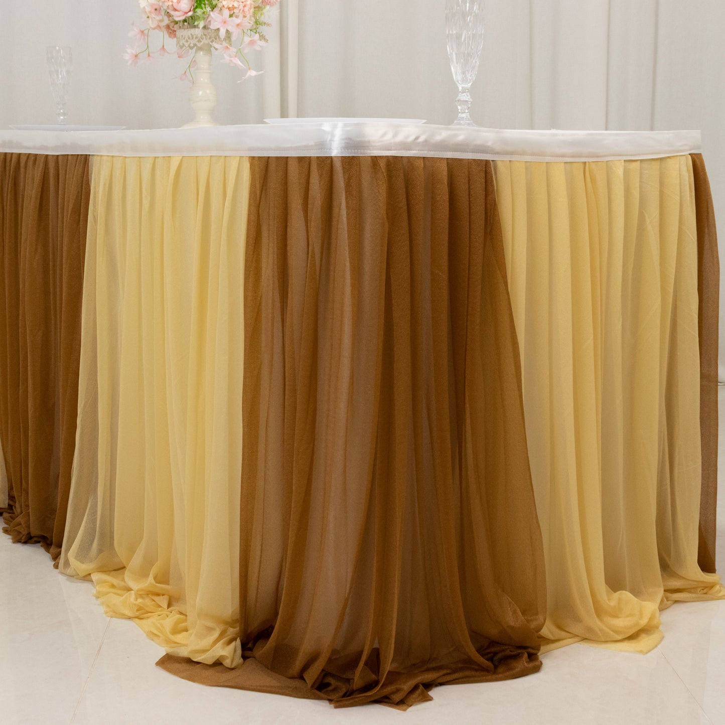 Elegant gold table skirt with layered fabric in yellow and brown tones.