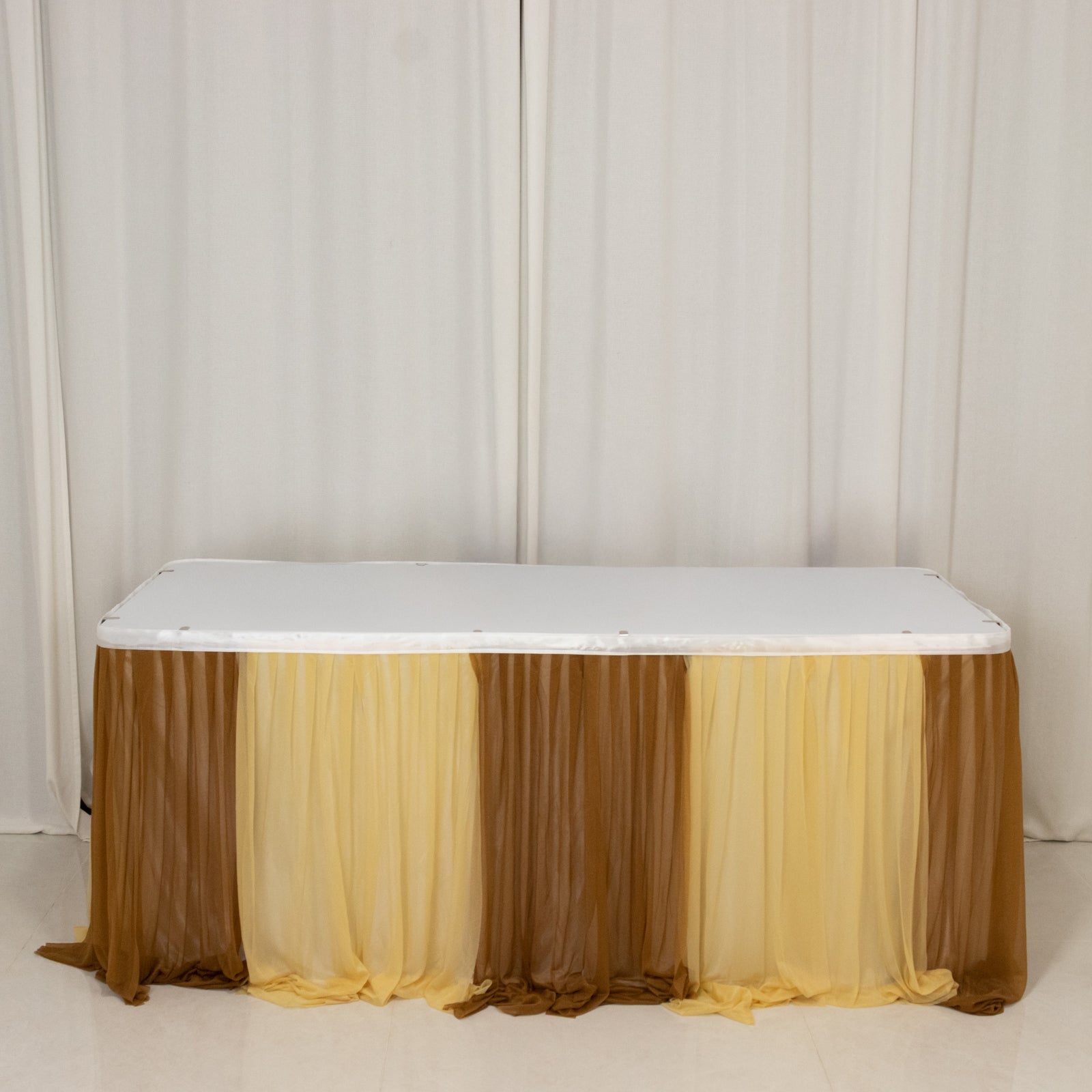 Gold table skirt with layered fabric drapes for elegant event decor.