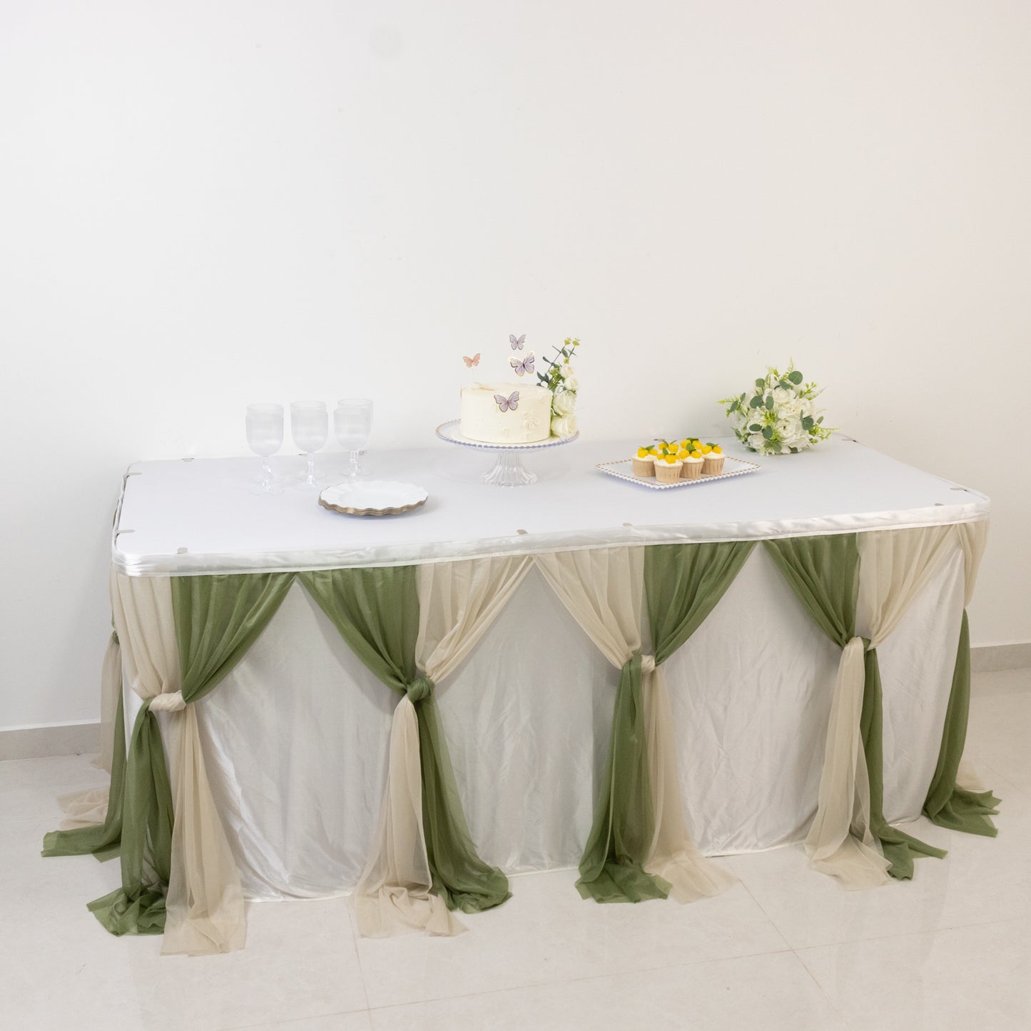 Elegant table setup with Dusty Sage drapes and a cake for a stylish celebration.