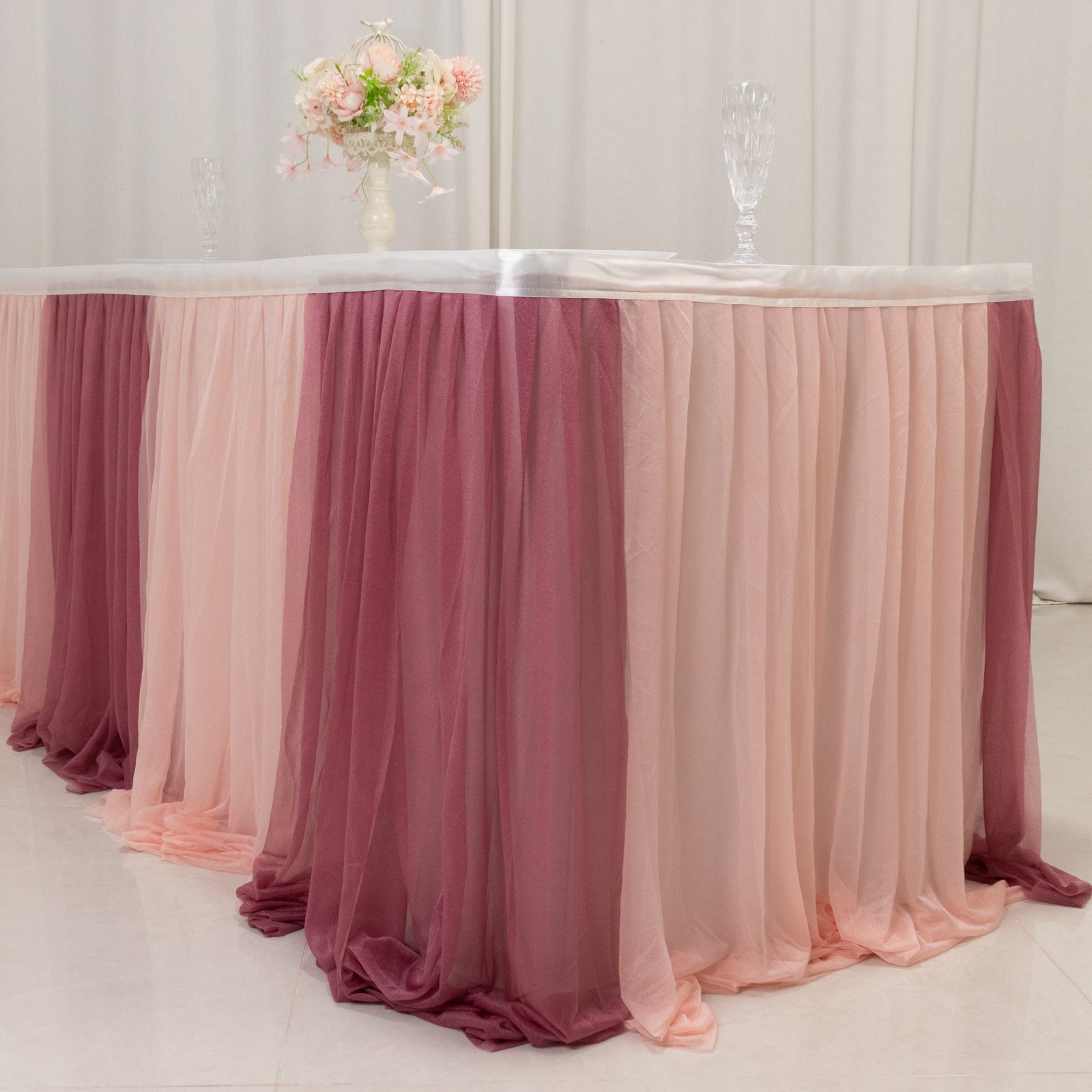 Blush colored table skirt with layered sheer fabric for elegant event decor.