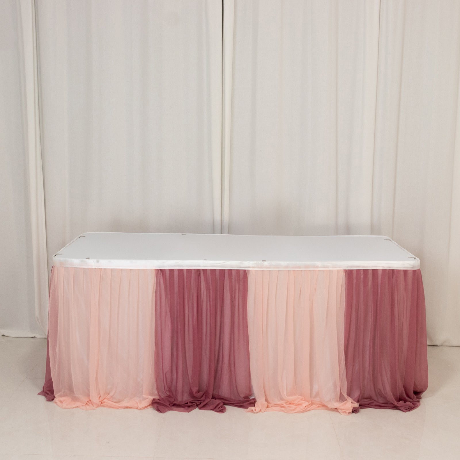 Blush table skirt with gradient draping for elegant event decor.