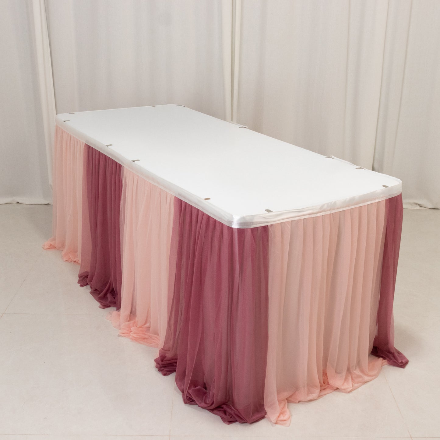 Blush ombre table skirt draped elegantly over a white table. Perfect for events.