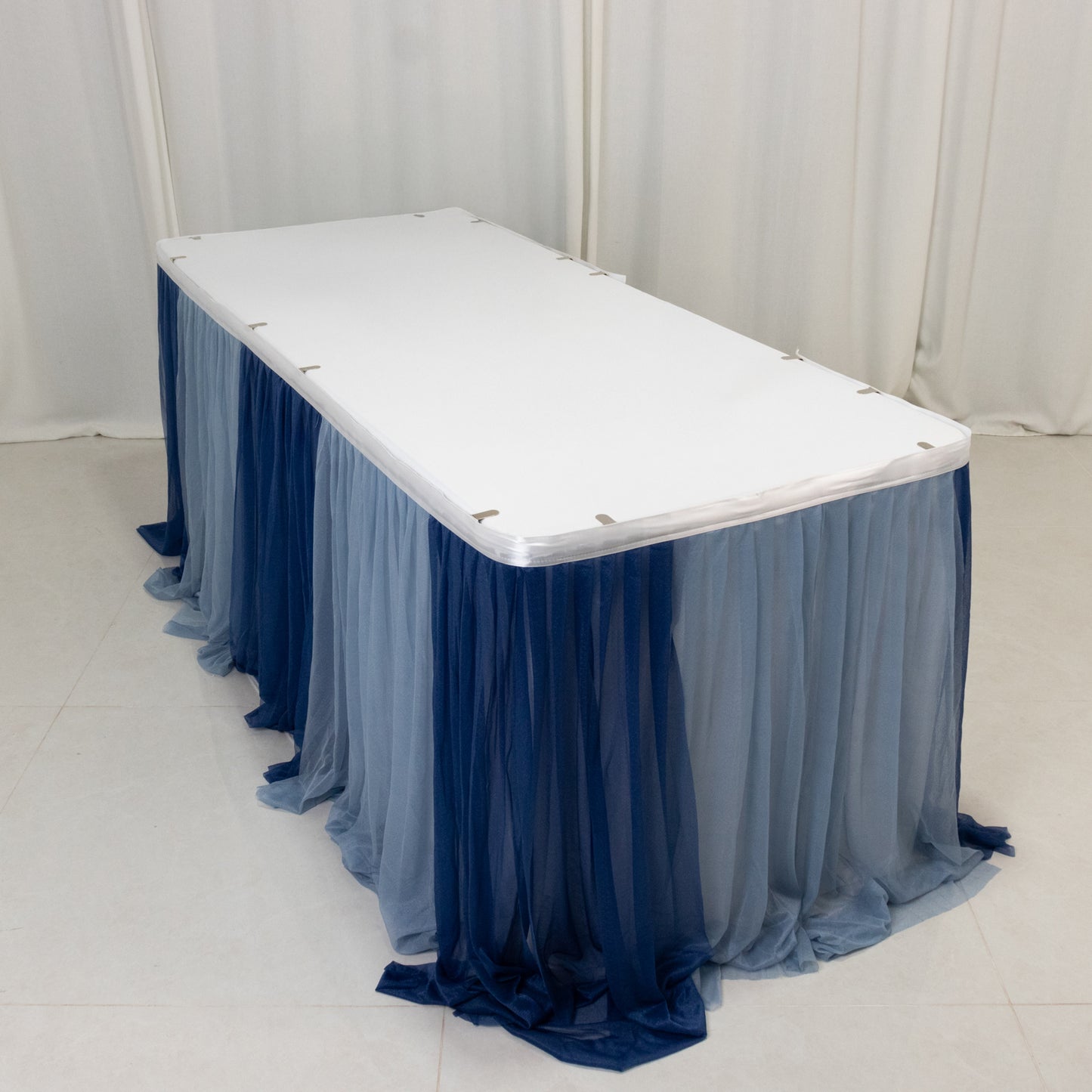 Navy blue and dusty blue sheer pleated ruffle table skirt on a white table.
