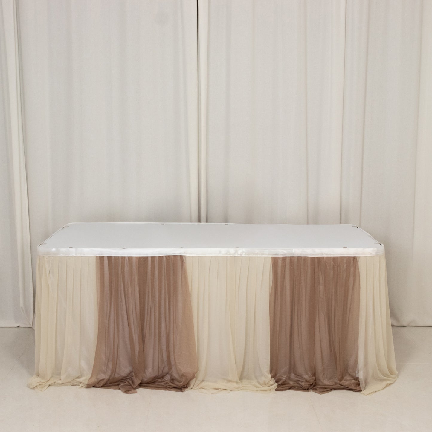 Beige table drape with elegant sheer fabric for events and decor.