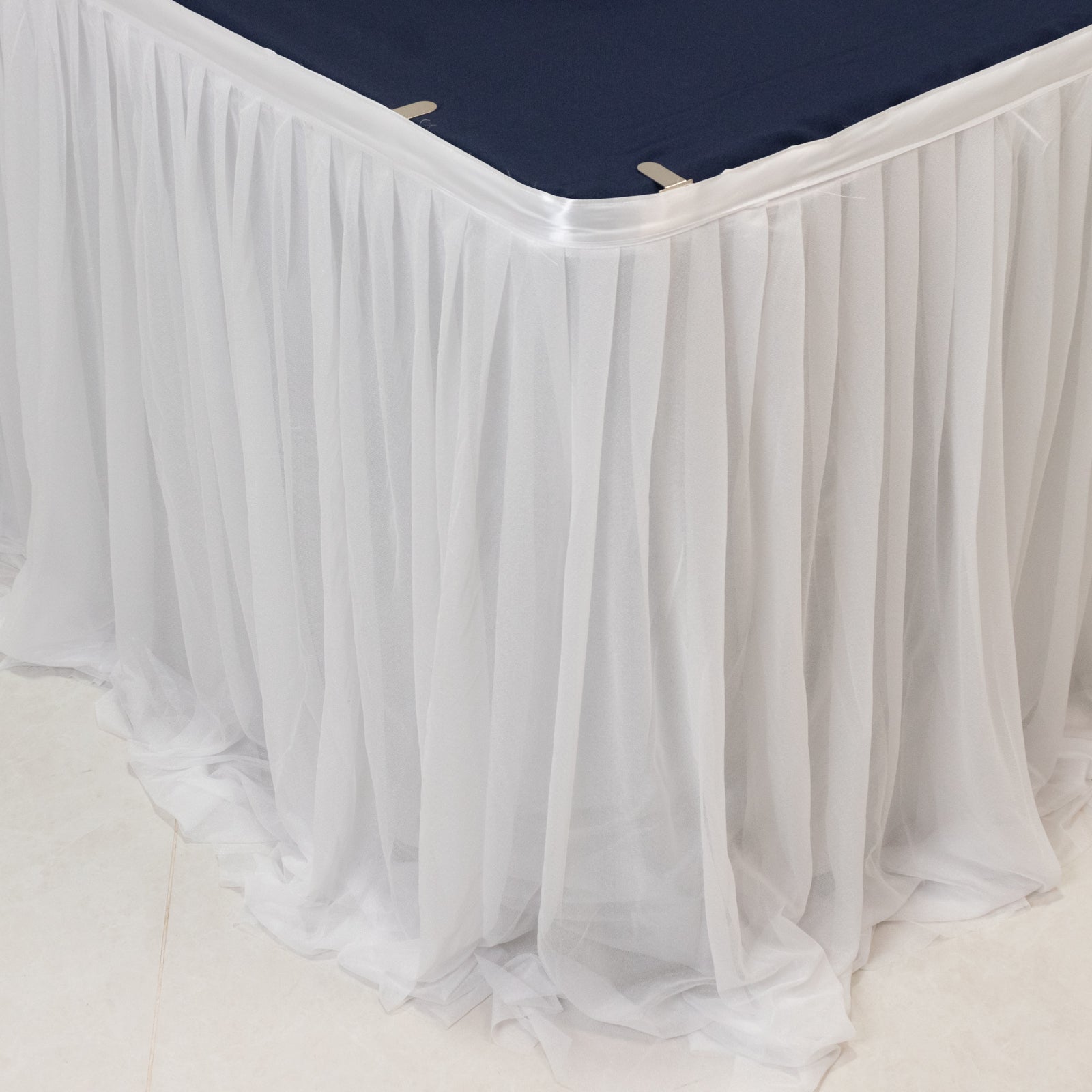 White table skirt draping elegantly over a navy tablecloth.