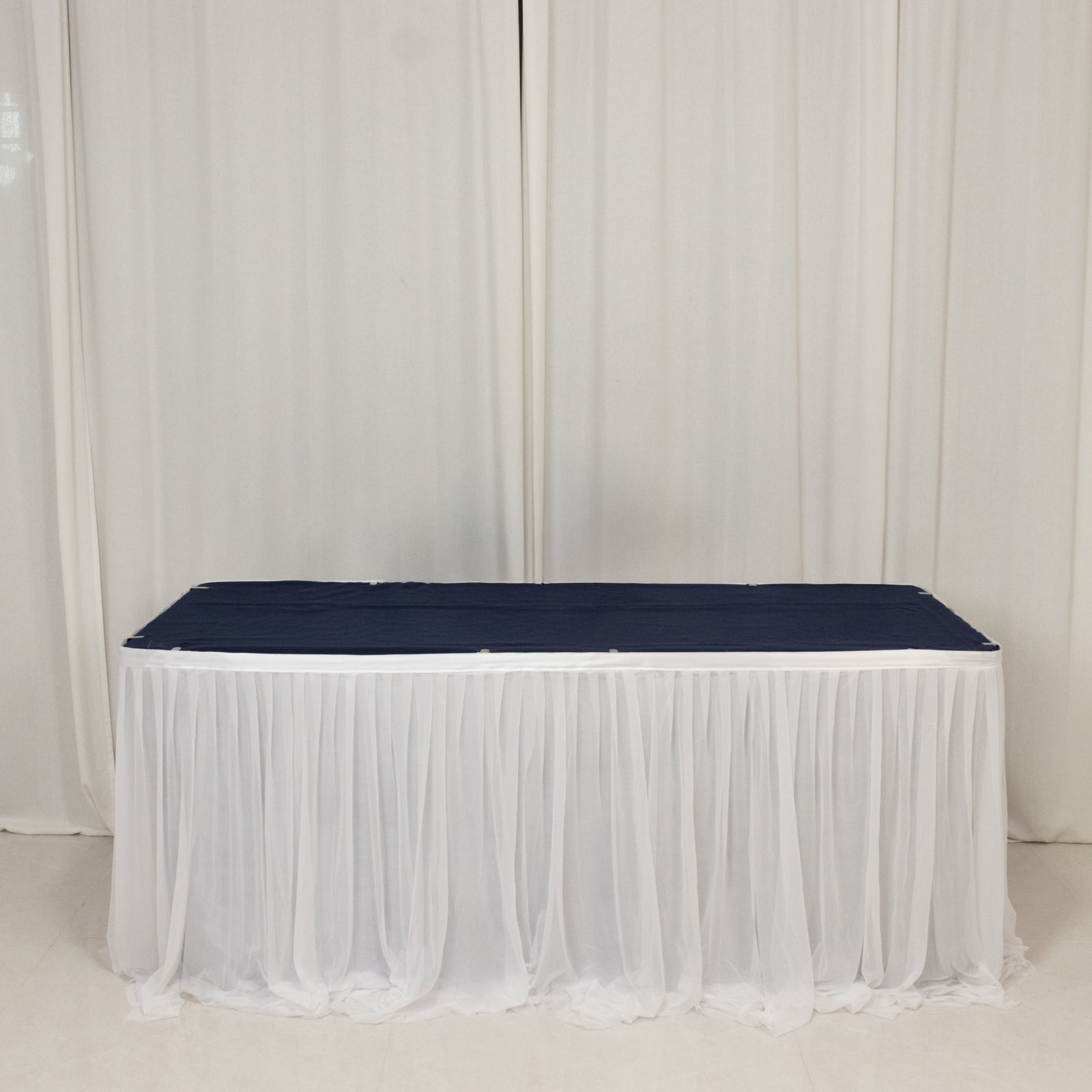 Elegant white table draping with a navy blue table runner for events.