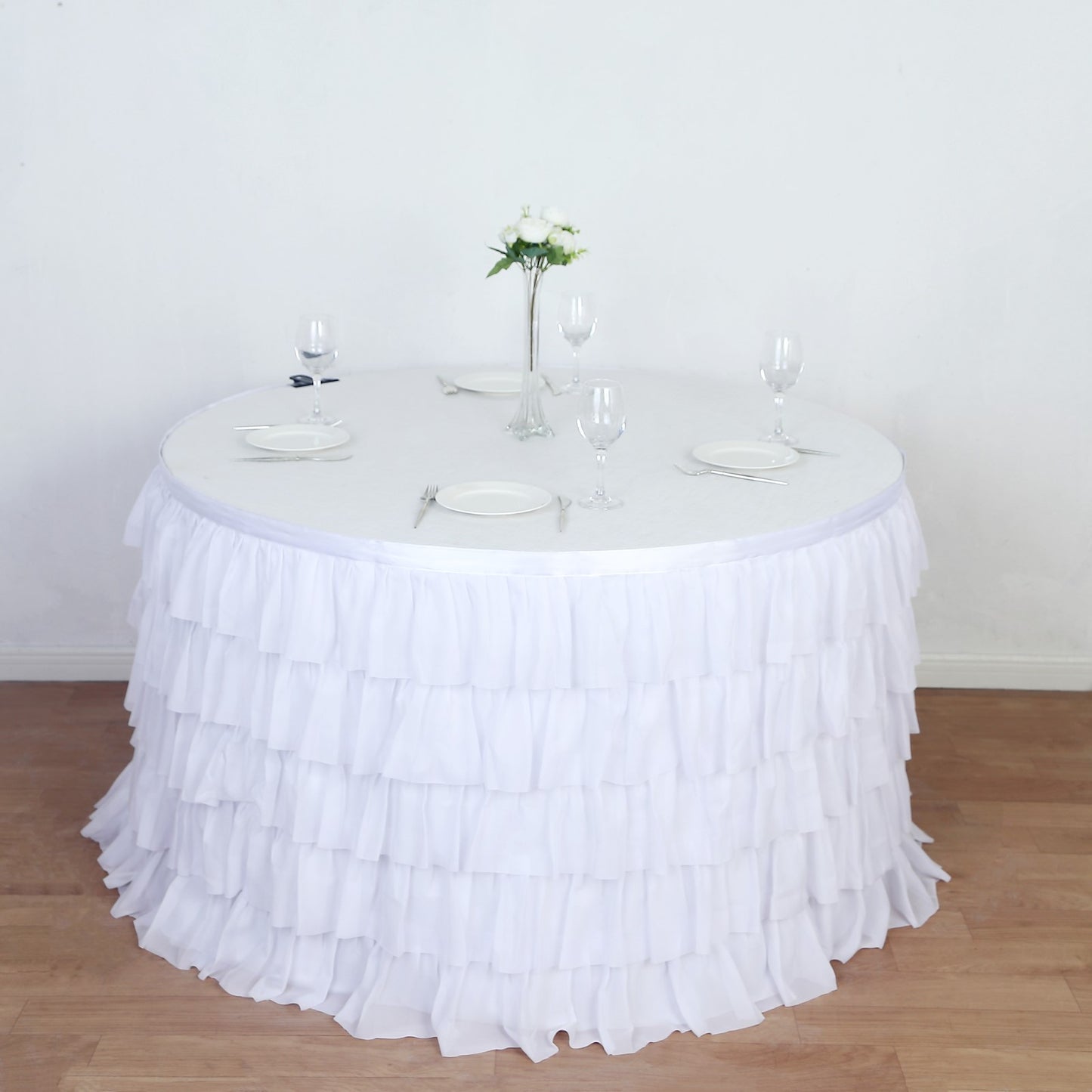 White ruffled tablecloth draping a round table set for an elegant dining experience.