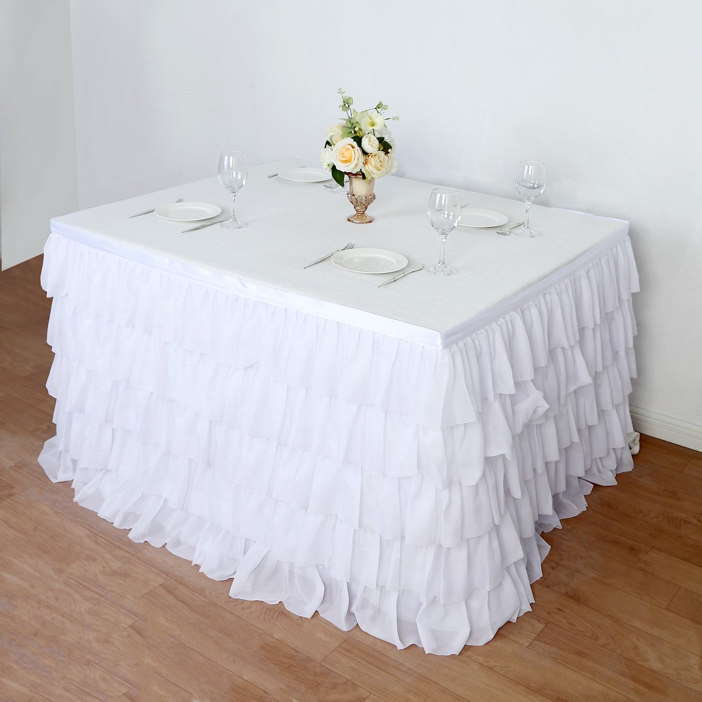 Elegant white ruffled table skirt for weddings and events with decorative centerpiece.