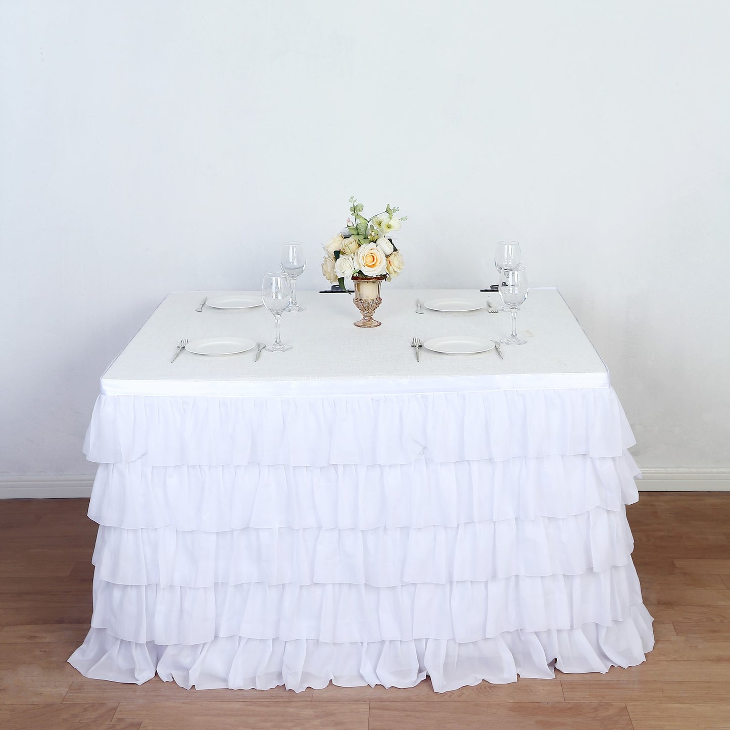 Elegant white ruffled tablecloth with floral centerpiece for special events.