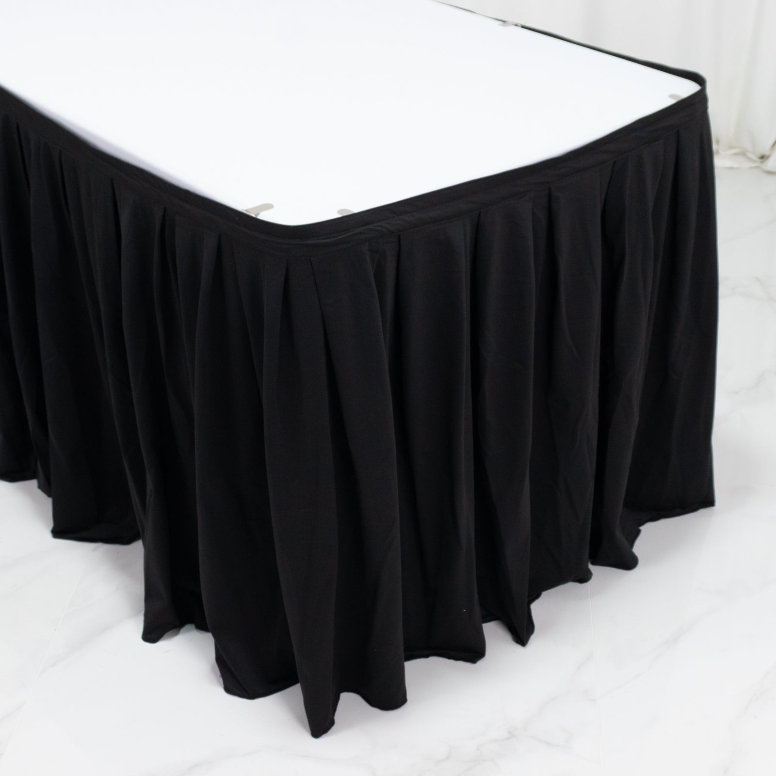 Black wrinkle-free event table skirt with shirred pleat design.