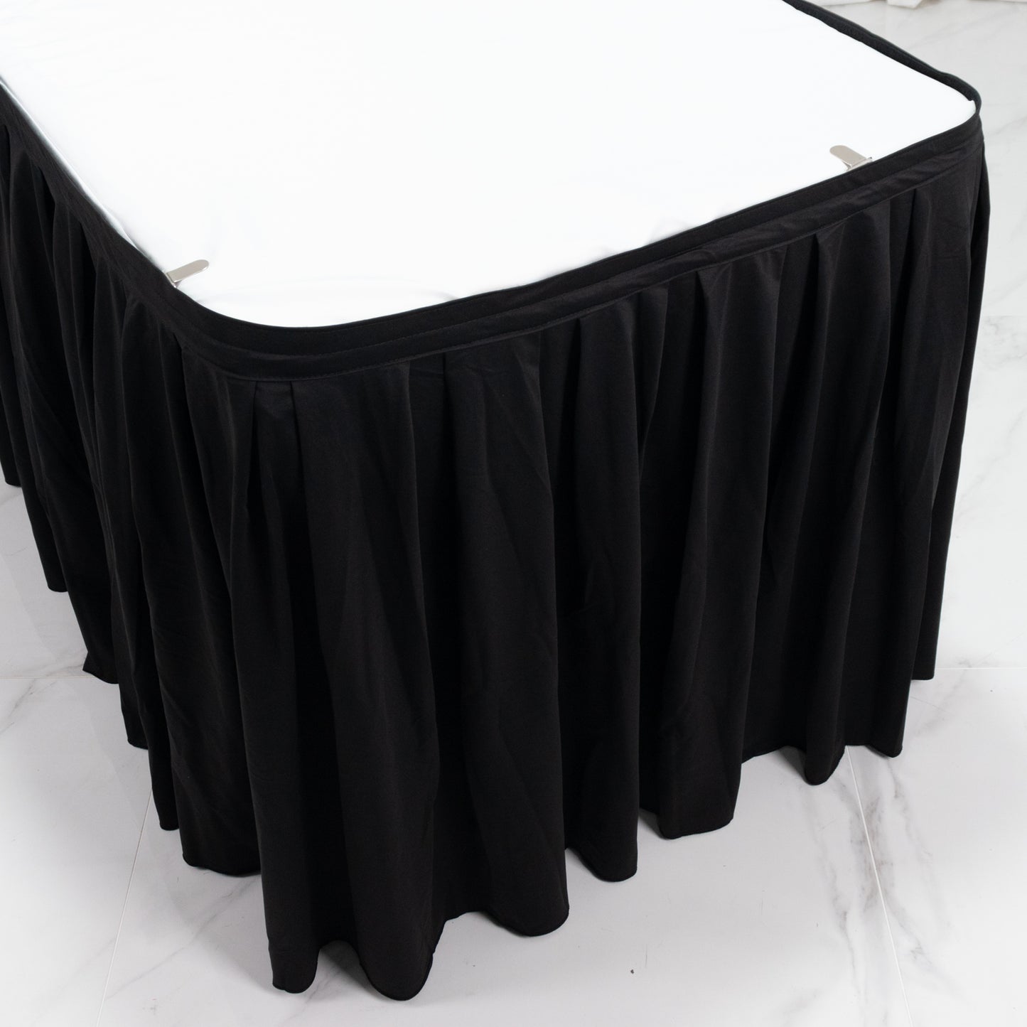 Black shirred pleat table skirt for events, wrinkle-free and stain-resistant.