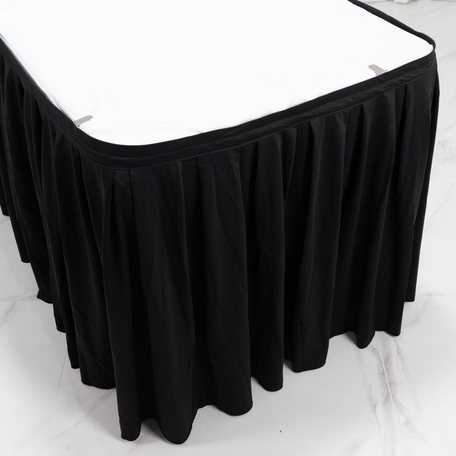 Black shirred pleat table skirt for events, wrinkle-free and stain-resistant.
