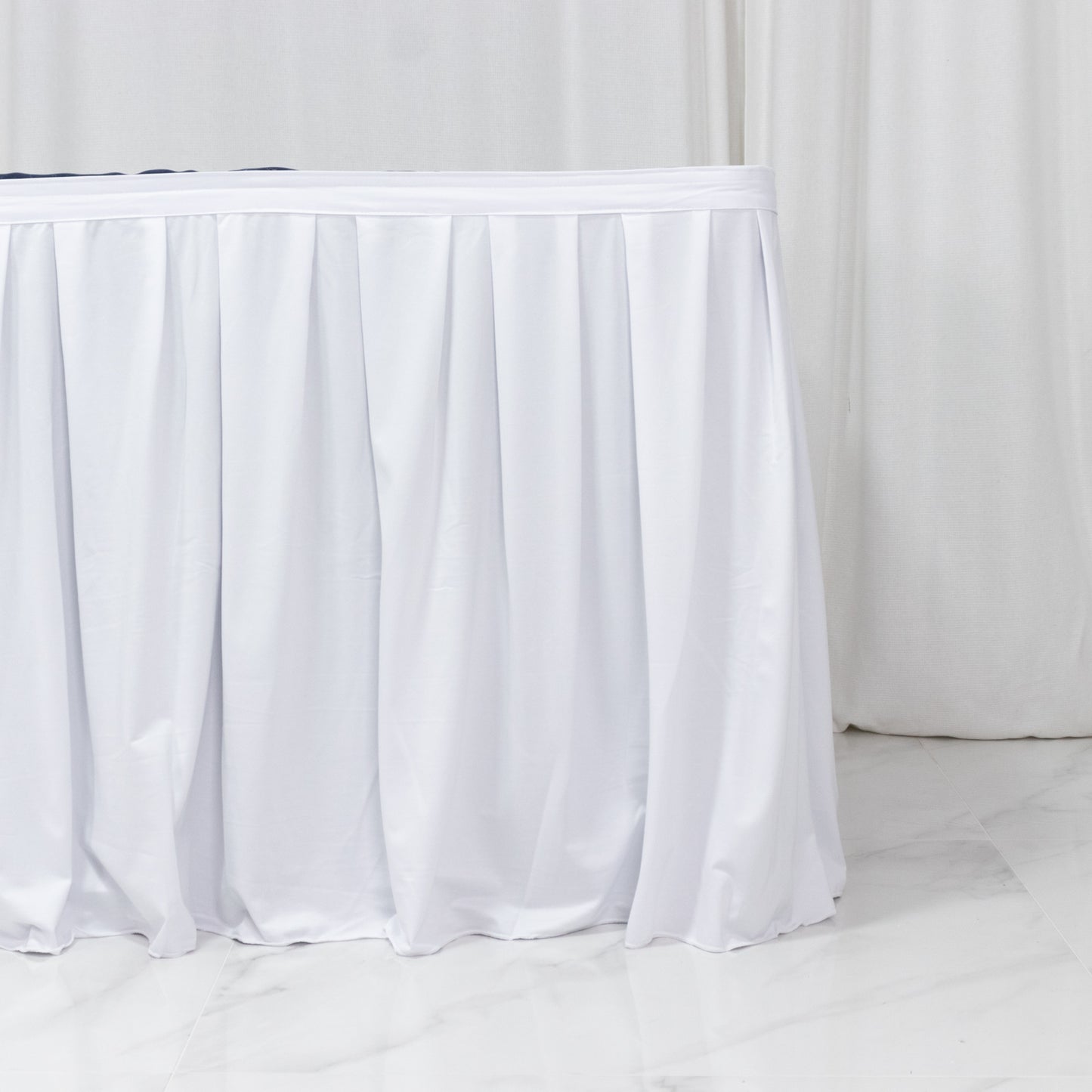 White pleated table skirt for events, wrinkle-free and stain-resistant.