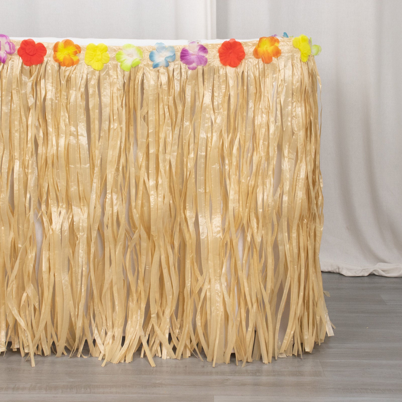 Natural raffia grass table skirt for Hawaiian themed party decorations.