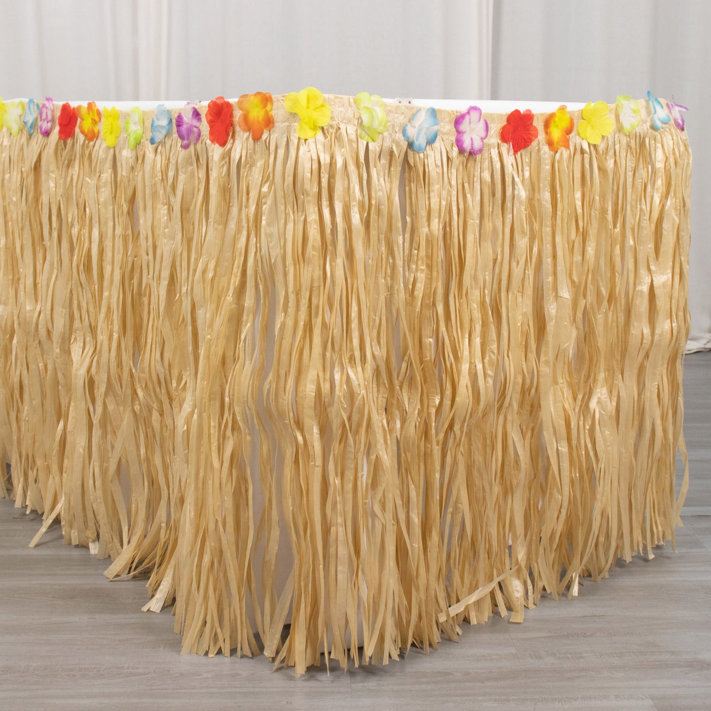 Natural raffia grass table skirt for Hawaiian themed party decorations.