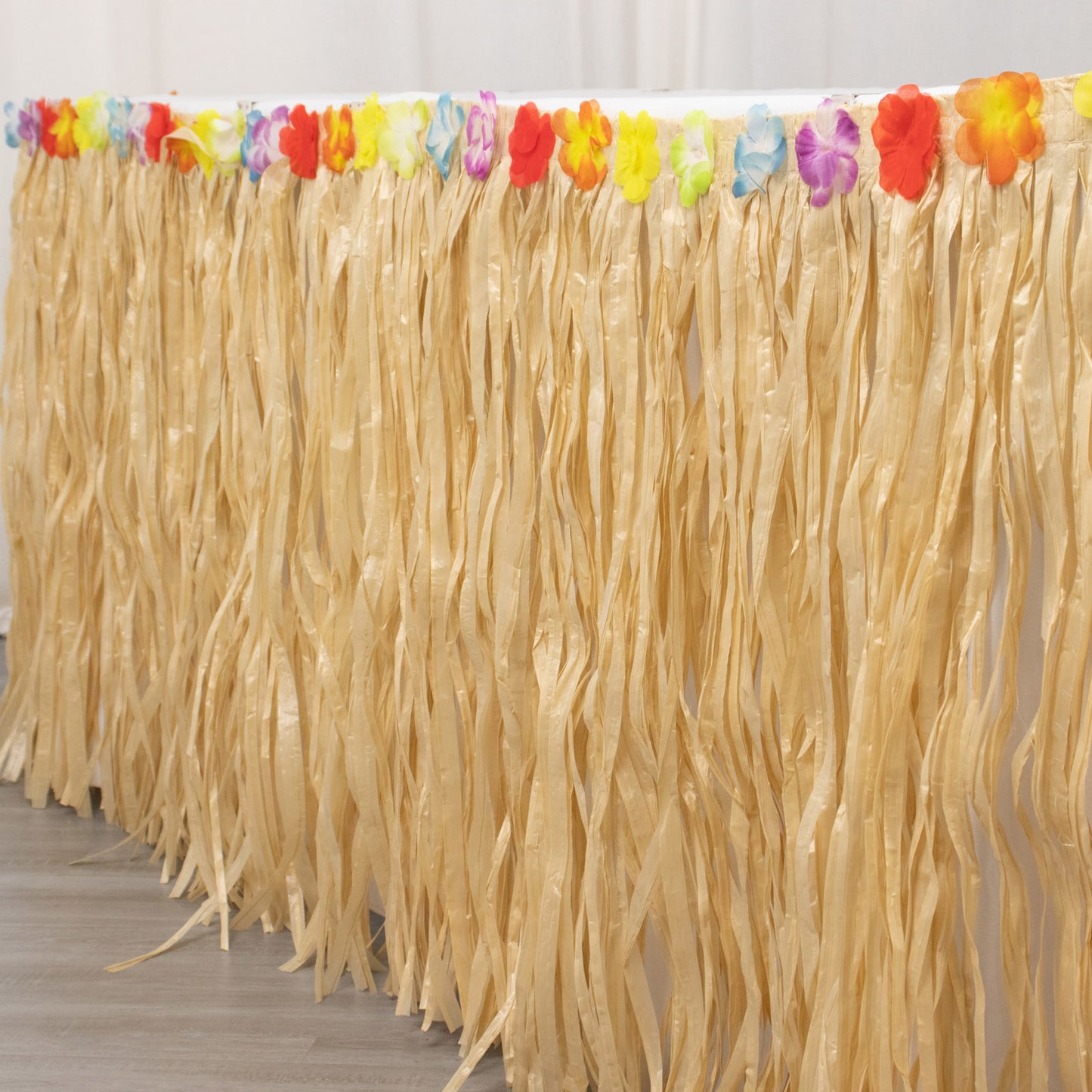 Natural raffia grass table skirt for Hawaiian themed party decorations.