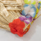 Natural raffia grass table skirt with colorful flower accents for luau decorations.