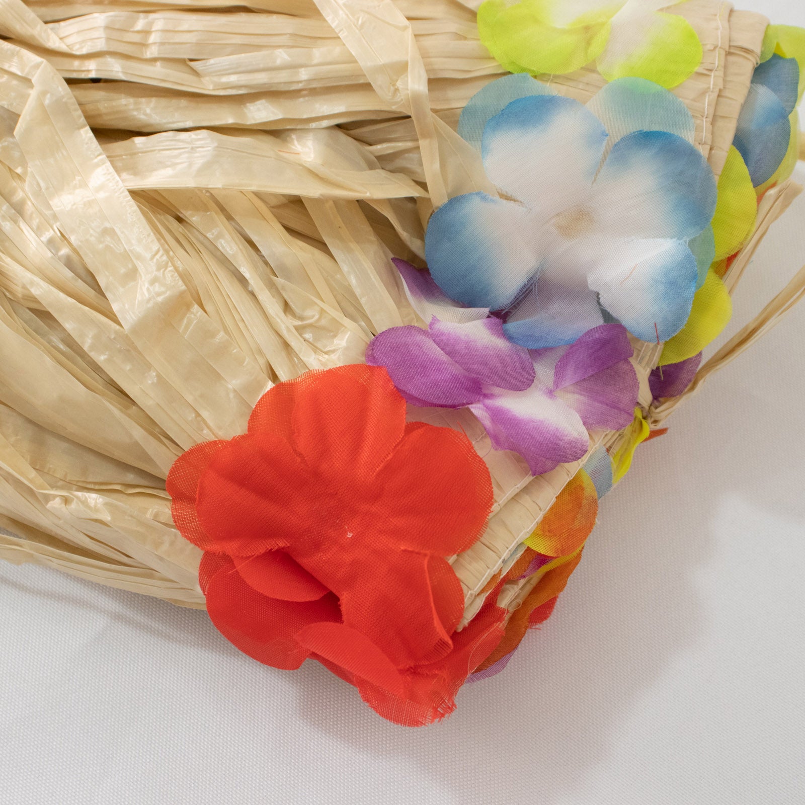 Natural raffia grass table skirt with colorful flower accents for luau decorations.