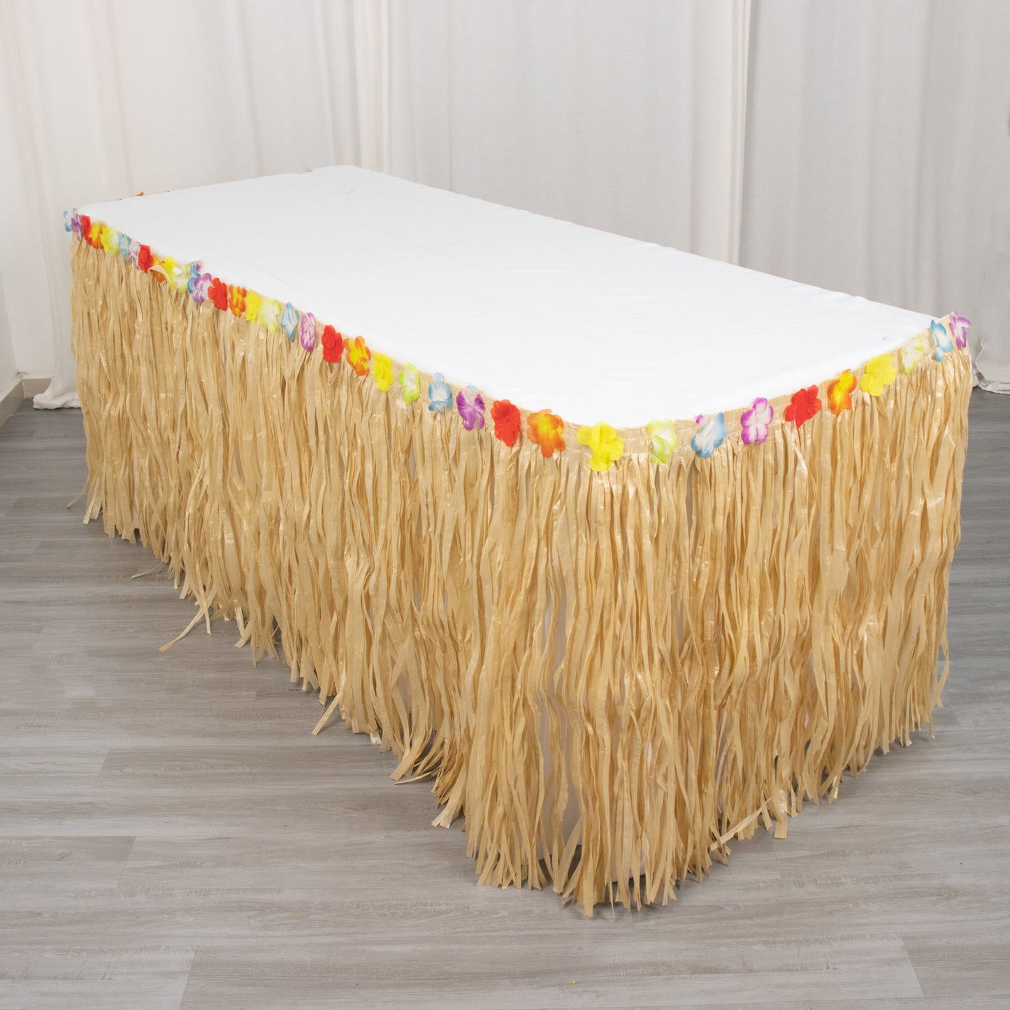 Natural raffia grass table skirt for Hawaiian themed party decorations.