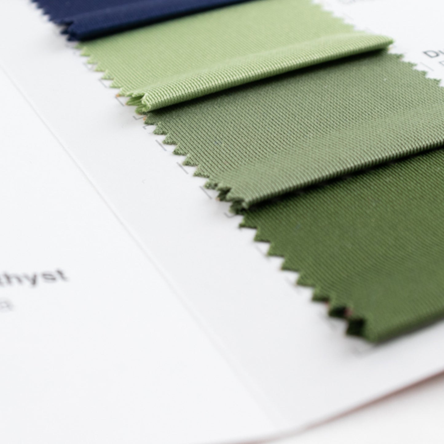 Green polyester fabric swatches from a sample book for upholstery and crafts.