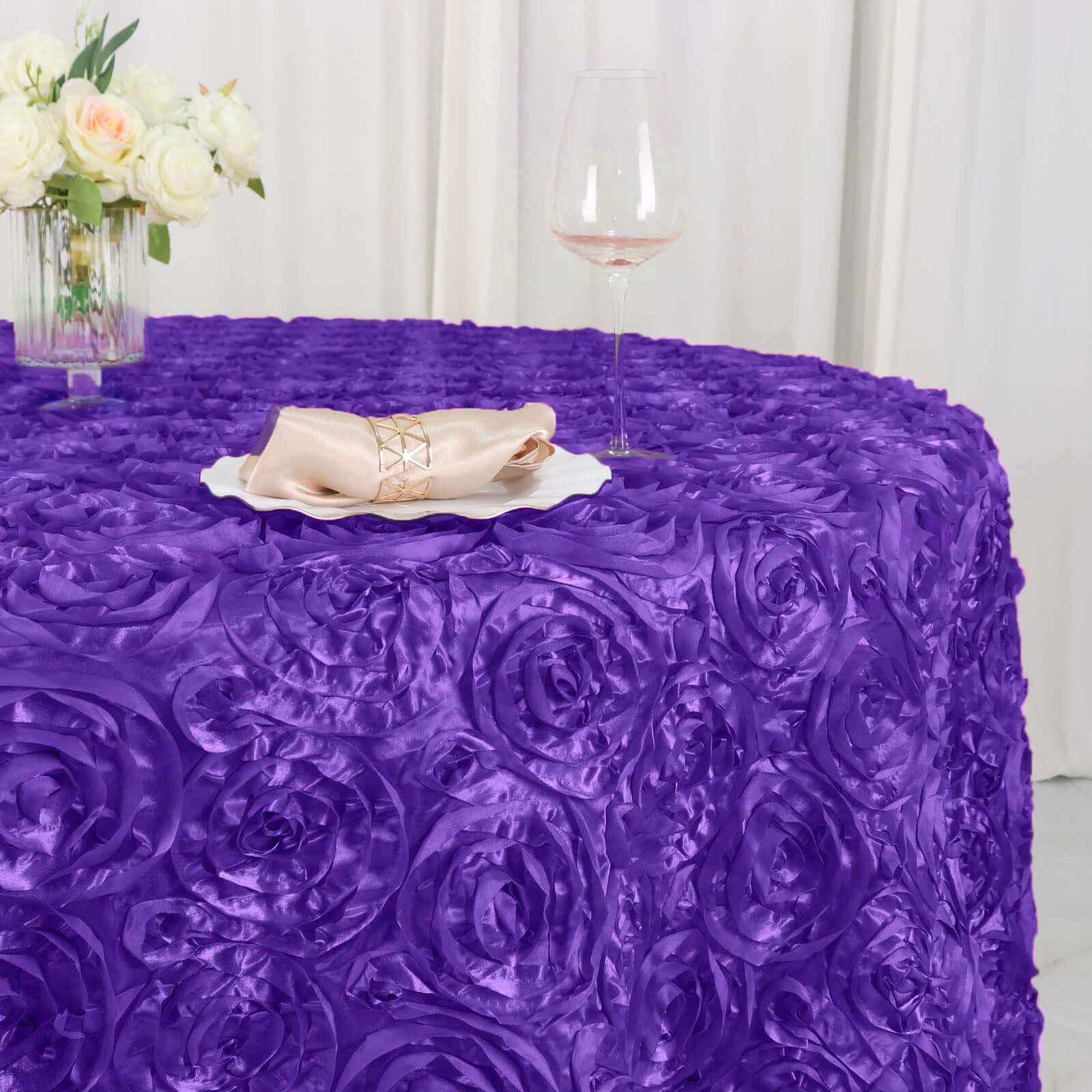 Purple satin round tablecloth with 3D rosettes for elegant table settings.