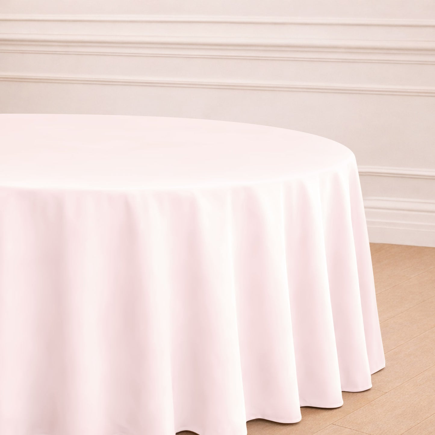 Blush round polyester tablecloth draping elegantly over a table.