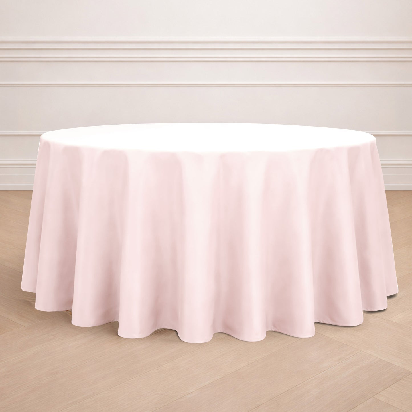 Blush round tablecloth on a wooden floor.