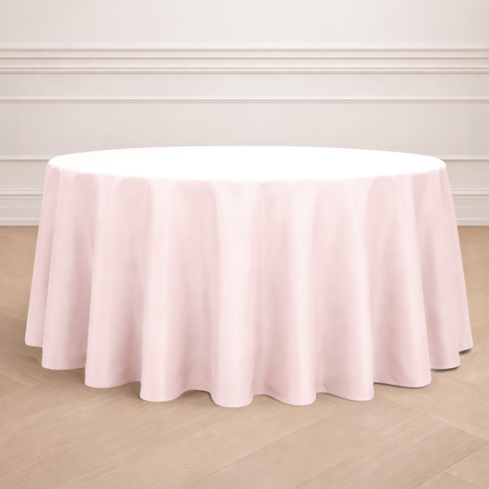 Blush round tablecloth on a wooden floor.