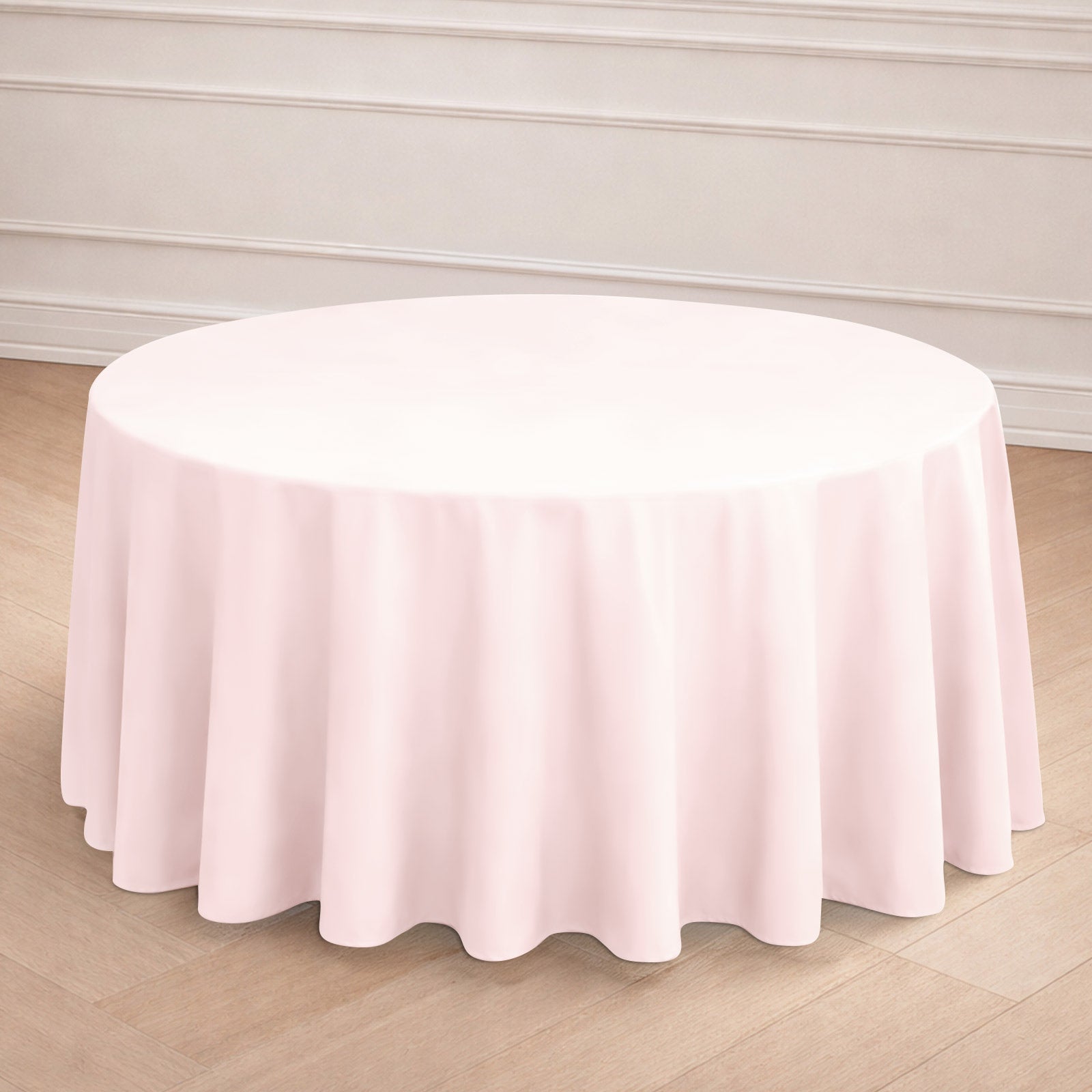 Blush round seamless polyester tablecloth on a wooden floor.