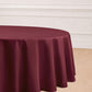 Burgundy seamless polyester round tablecloth on a wooden floor.