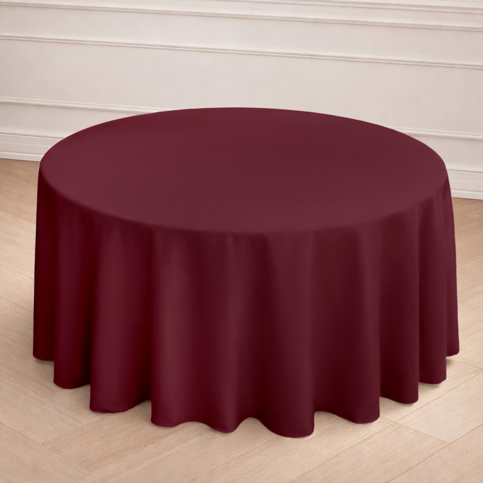 Burgundy seamless polyester round tablecloth on a wooden floor.