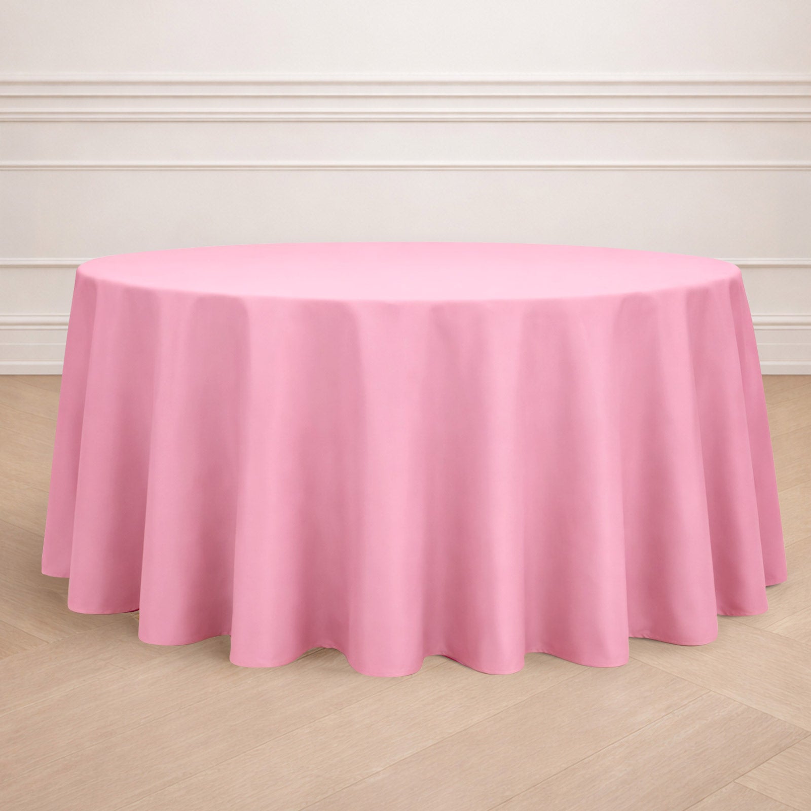 120" Pink Seamless Polyester Round Tablecloth on a wooden floor.