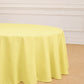 Yellow round polyester tablecloth on a wooden floor.