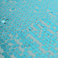 Turquoise sequin tablecloth with a shiny, reflective surface.