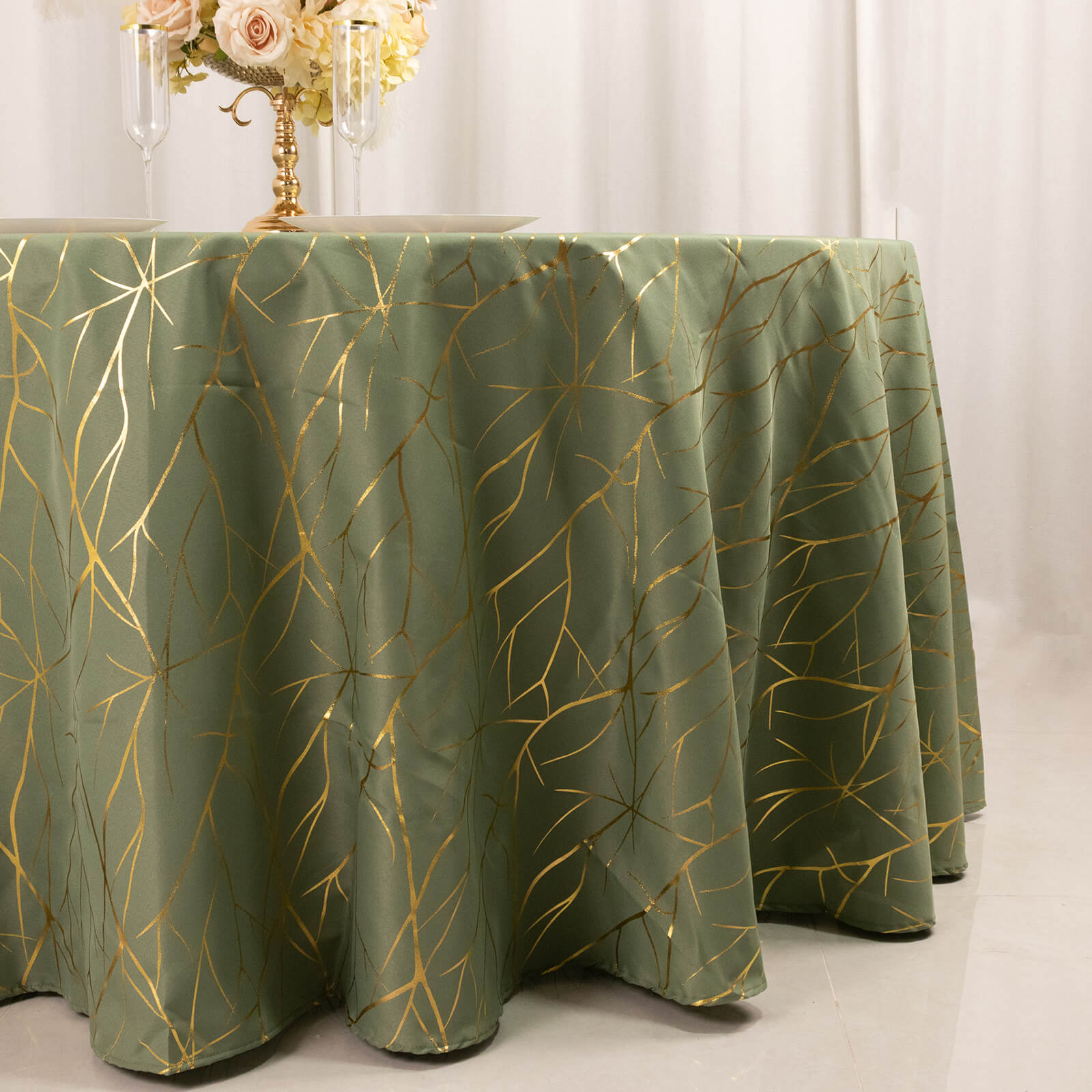 Dusty sage green round tablecloth with gold foil tree branch pattern.