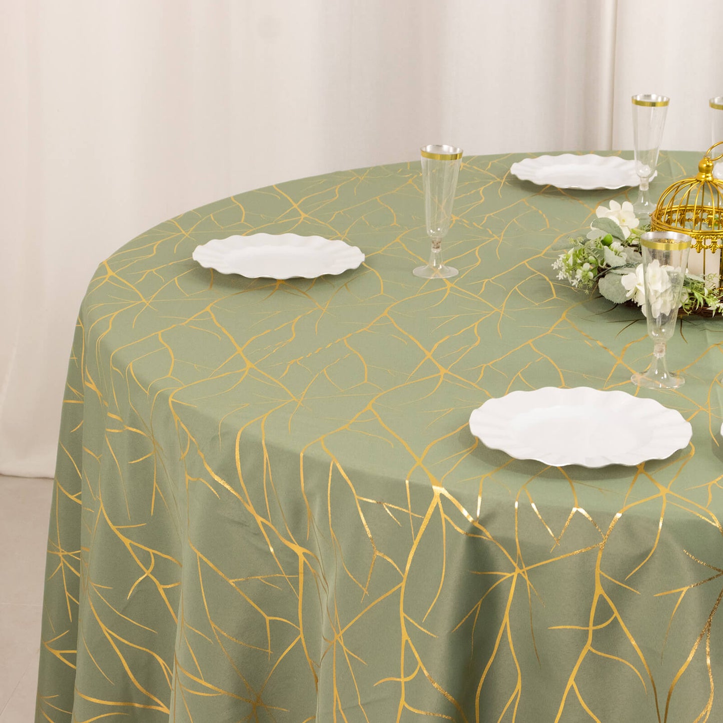 Dusty sage green round tablecloth with gold foil tree branch pattern.