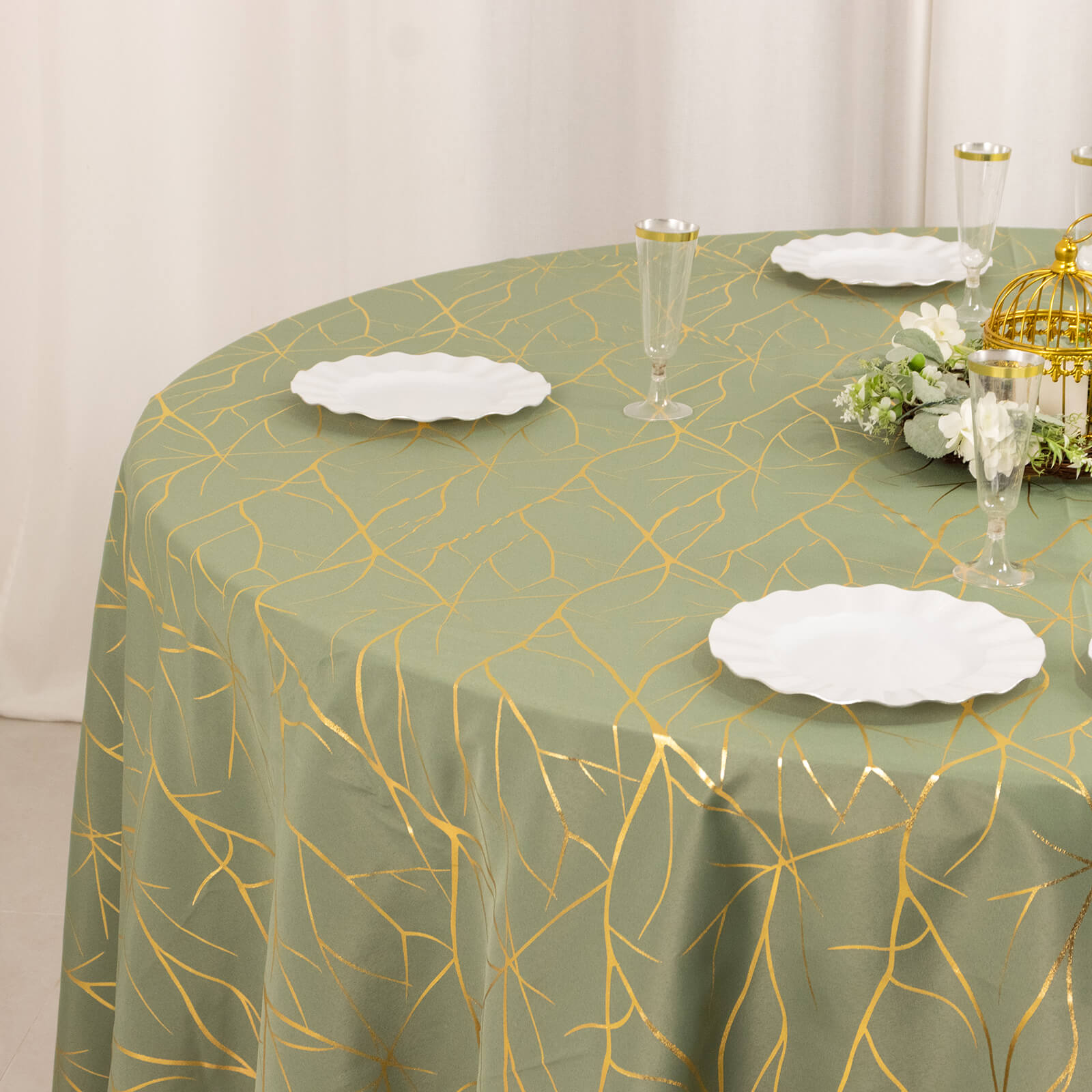 Dusty sage green round tablecloth with gold foil tree branch pattern.
