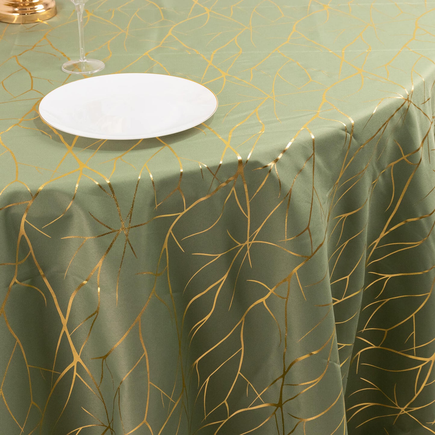 Dusty sage green round tablecloth with gold foil tree branch pattern.