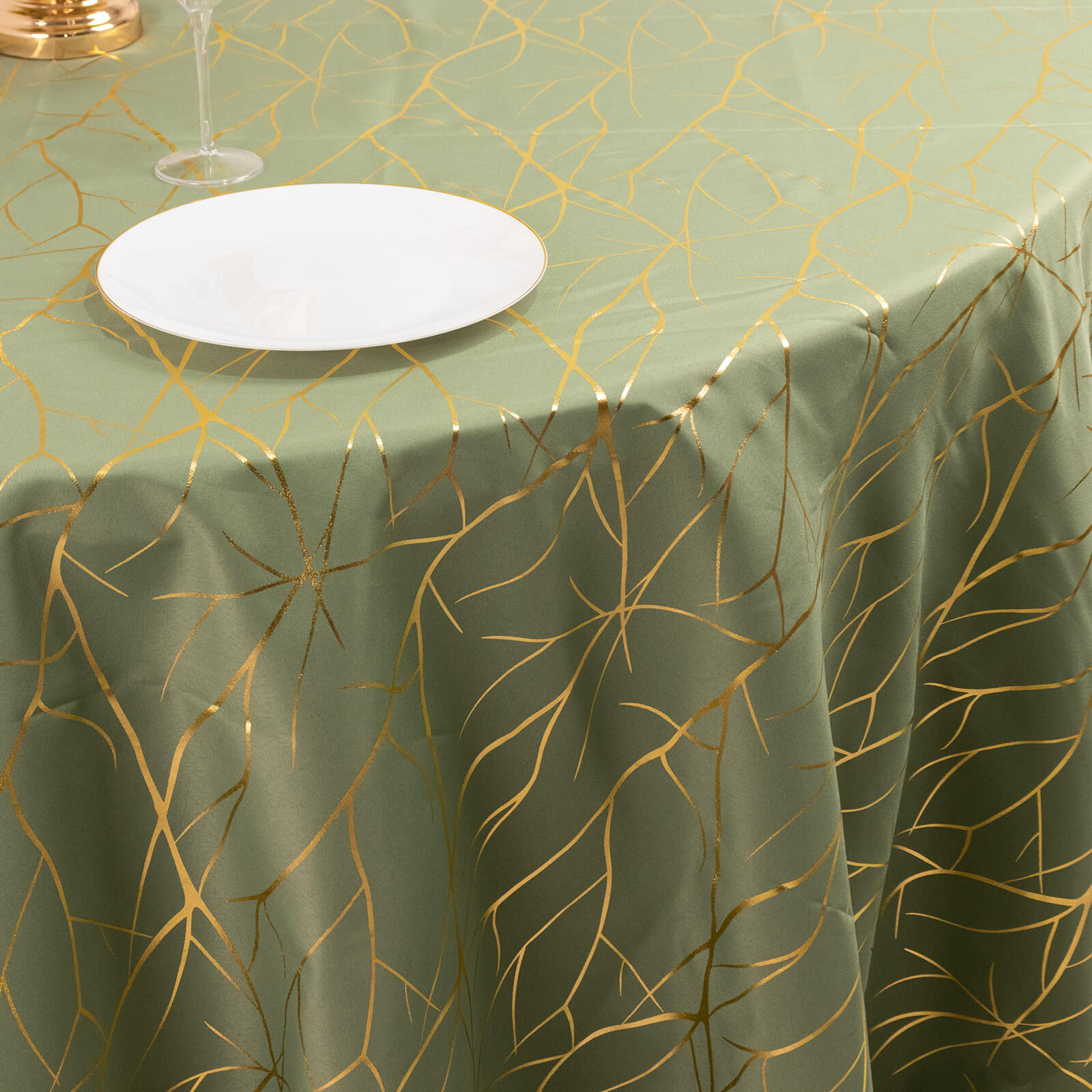 Dusty sage green round tablecloth with gold foil tree branch pattern.