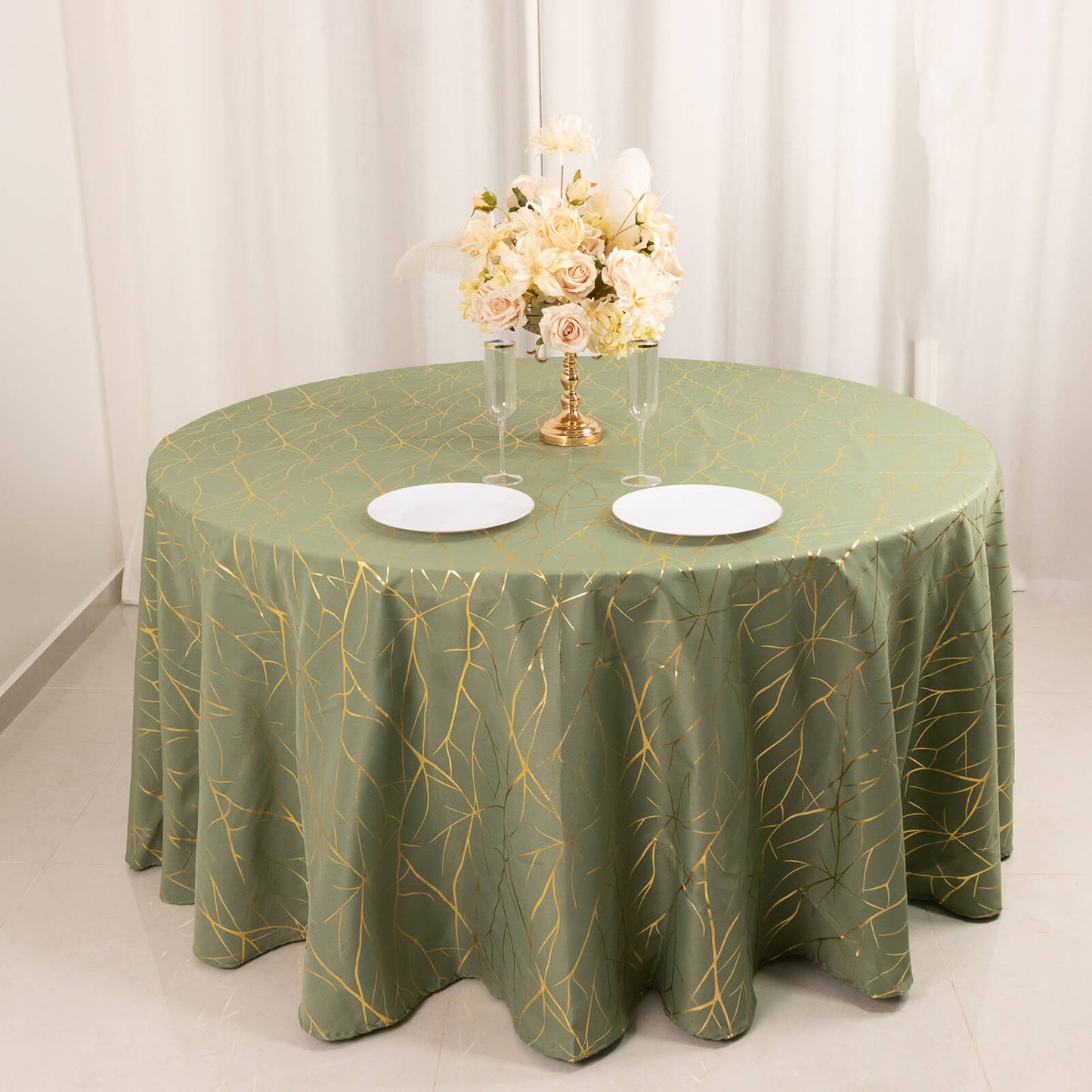 Dusty sage green round tablecloth with gold foil tree branch pattern.