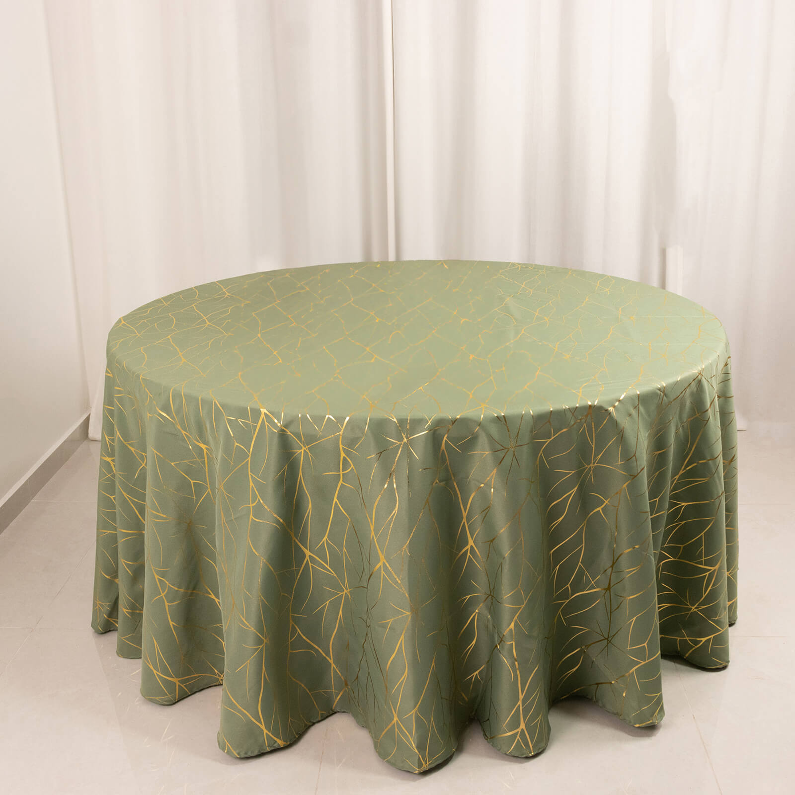 Dusty sage green round tablecloth with gold foil tree branch pattern.