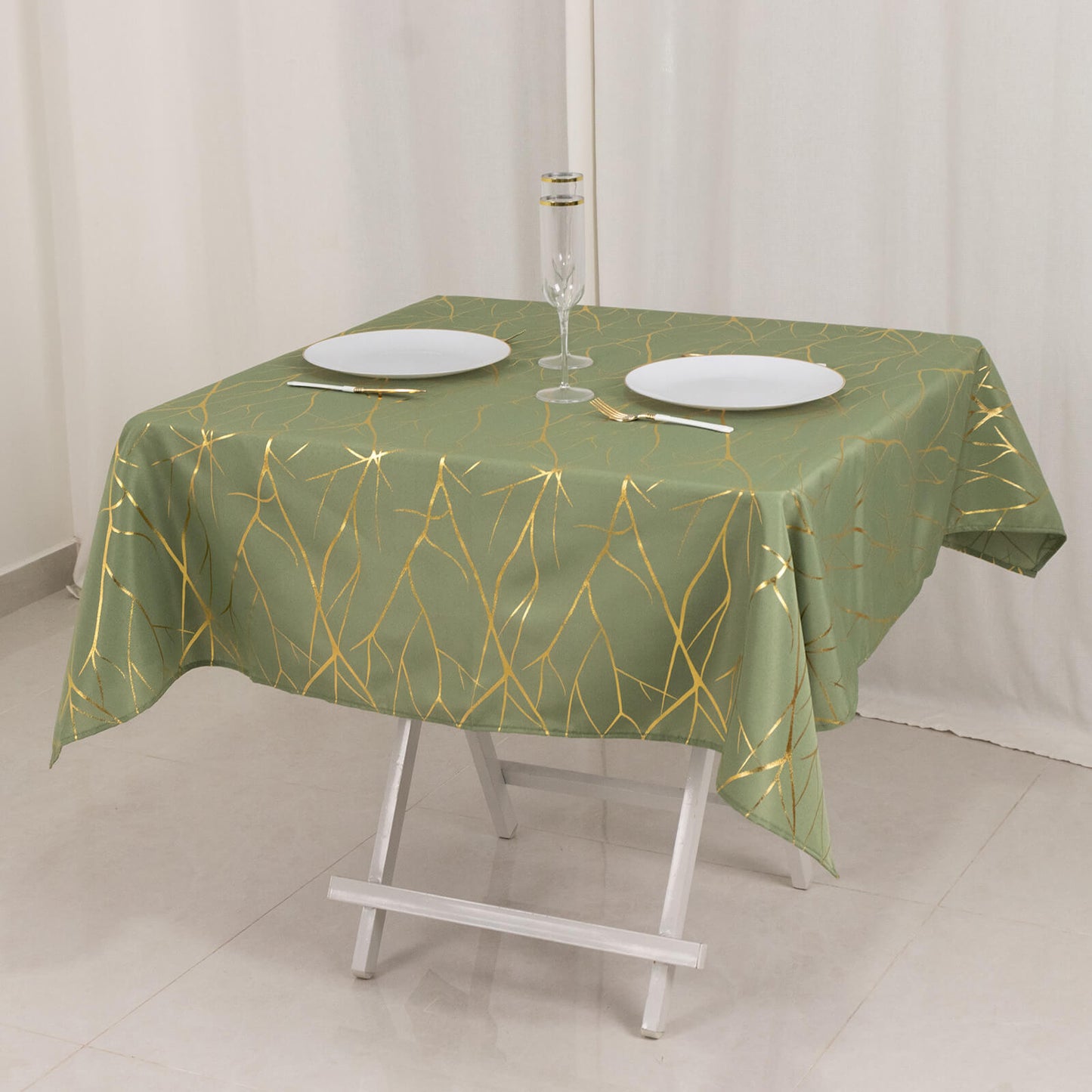 Dusty sage green tablecloth with gold foil tree branch pattern on a table.