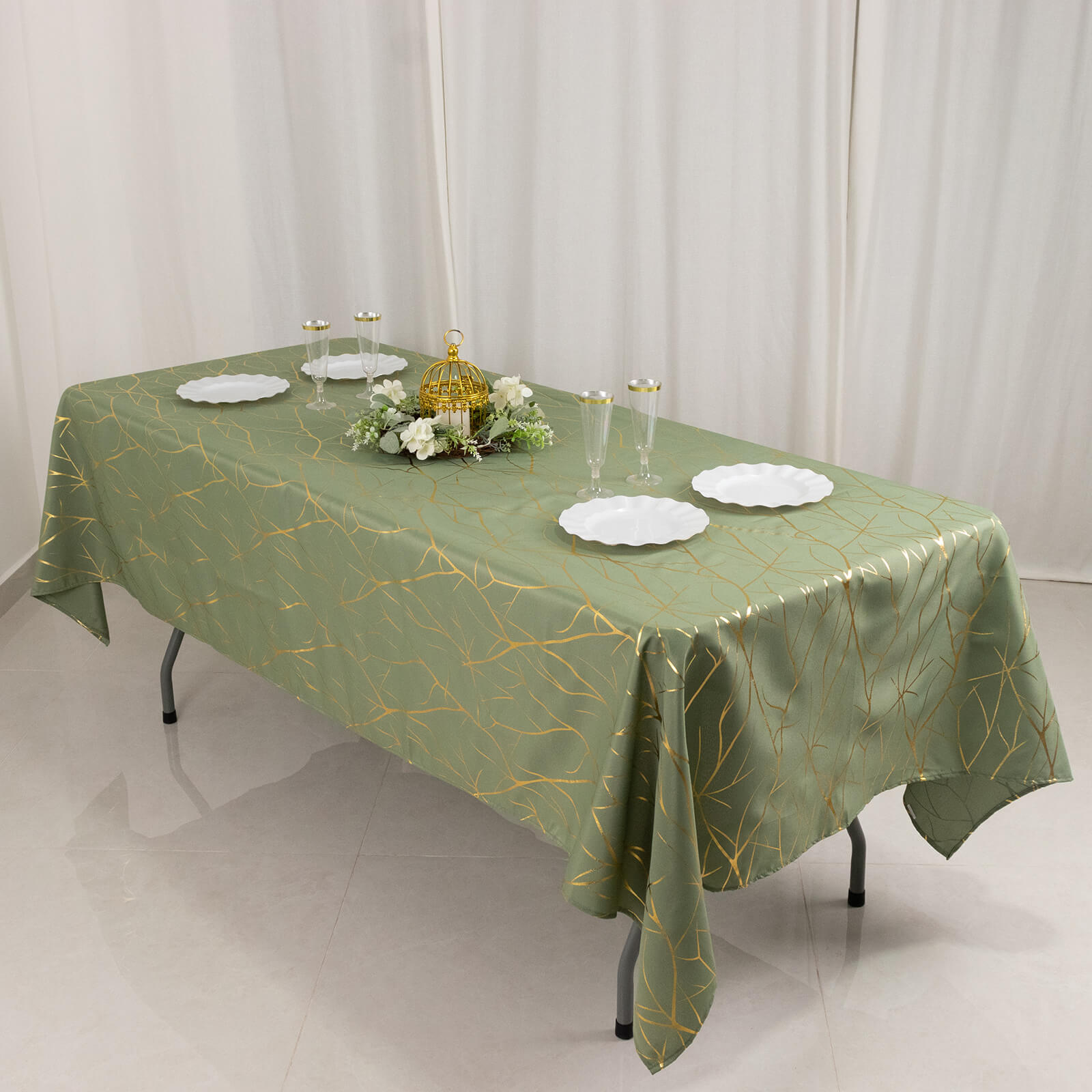 Dusty sage green tablecloth with gold foil tree branch pattern on a dining table.