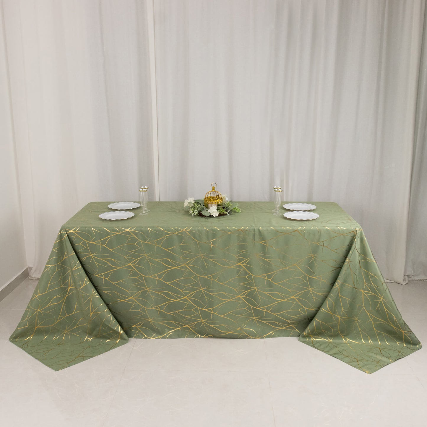 Dusty sage green tablecloth with gold foil tree branch pattern on a 6-foot table.