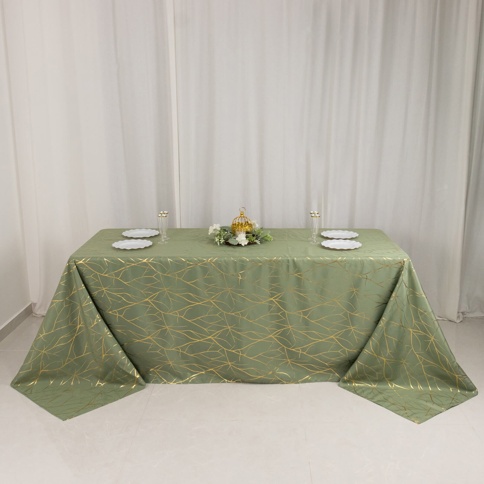 Dusty sage green tablecloth with gold foil tree branch pattern on a 6-foot table.