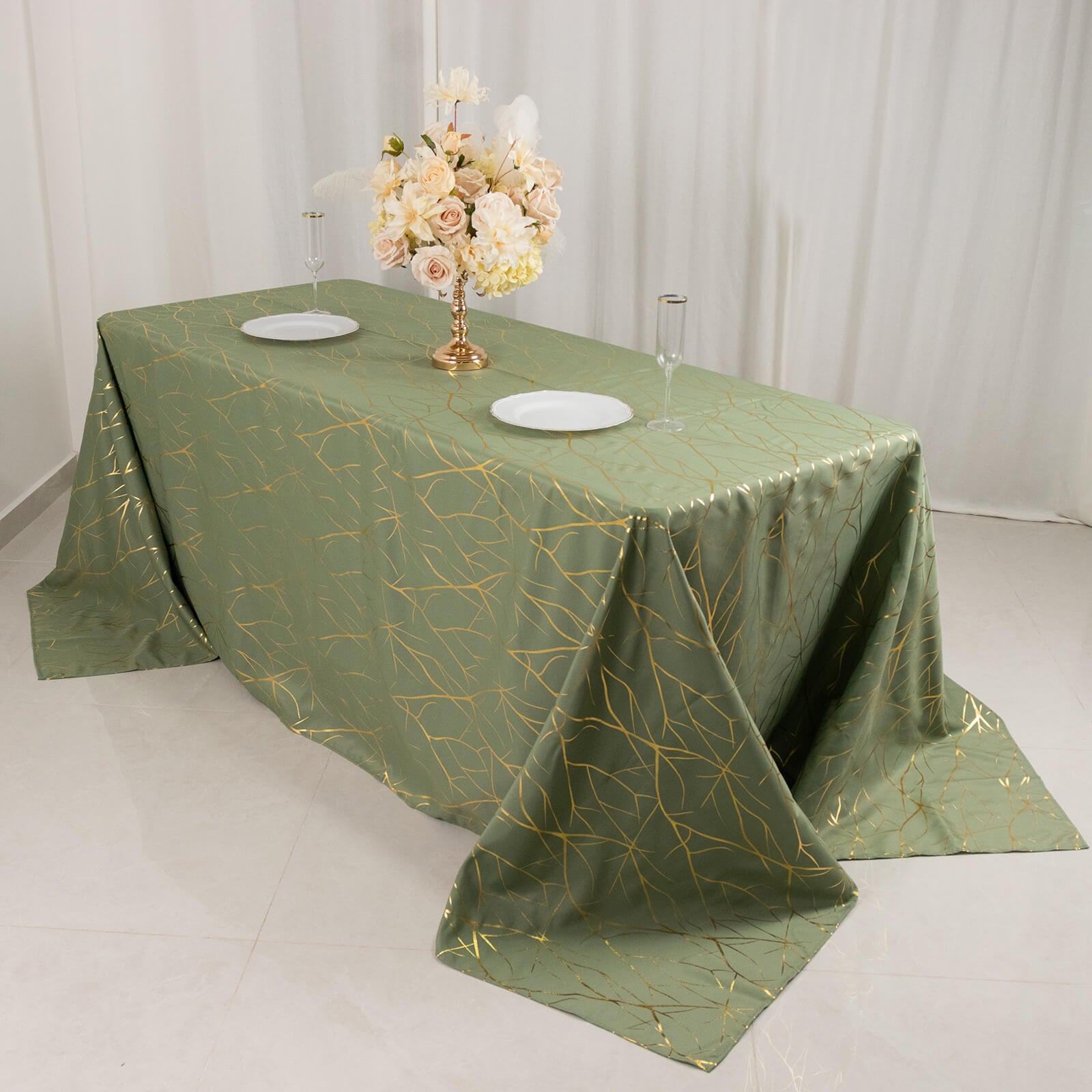 Dusty sage green tablecloth with gold foil tree branch pattern on a banquet table.